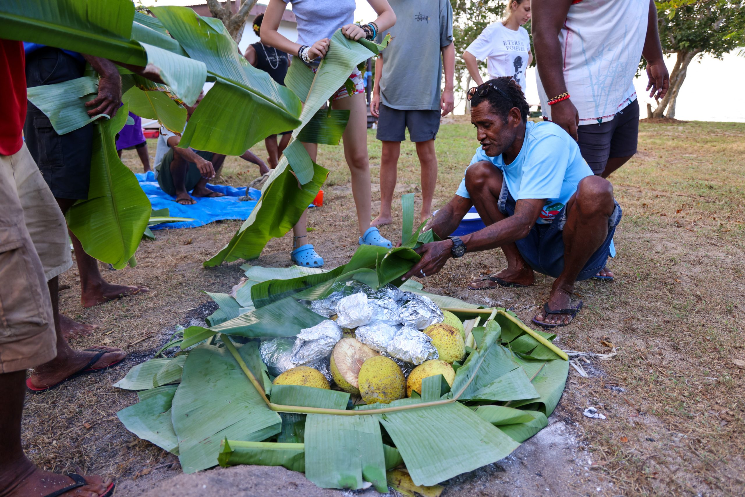 A local chef prepares a traditional Fijian meal wrapped in banana leaves over an open fire