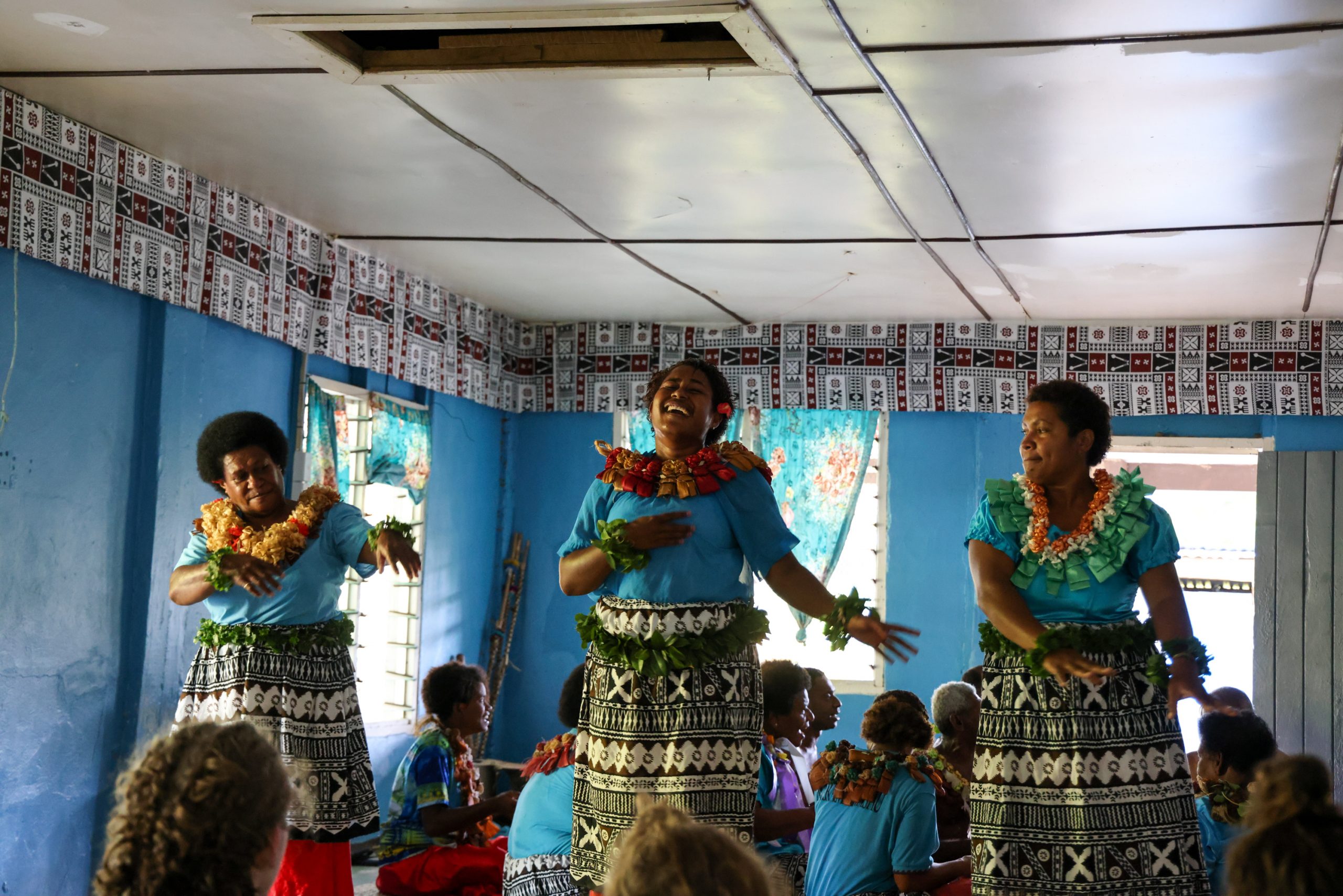 Fijian women in traditional dress and floral leis perform a dance for visiting students
