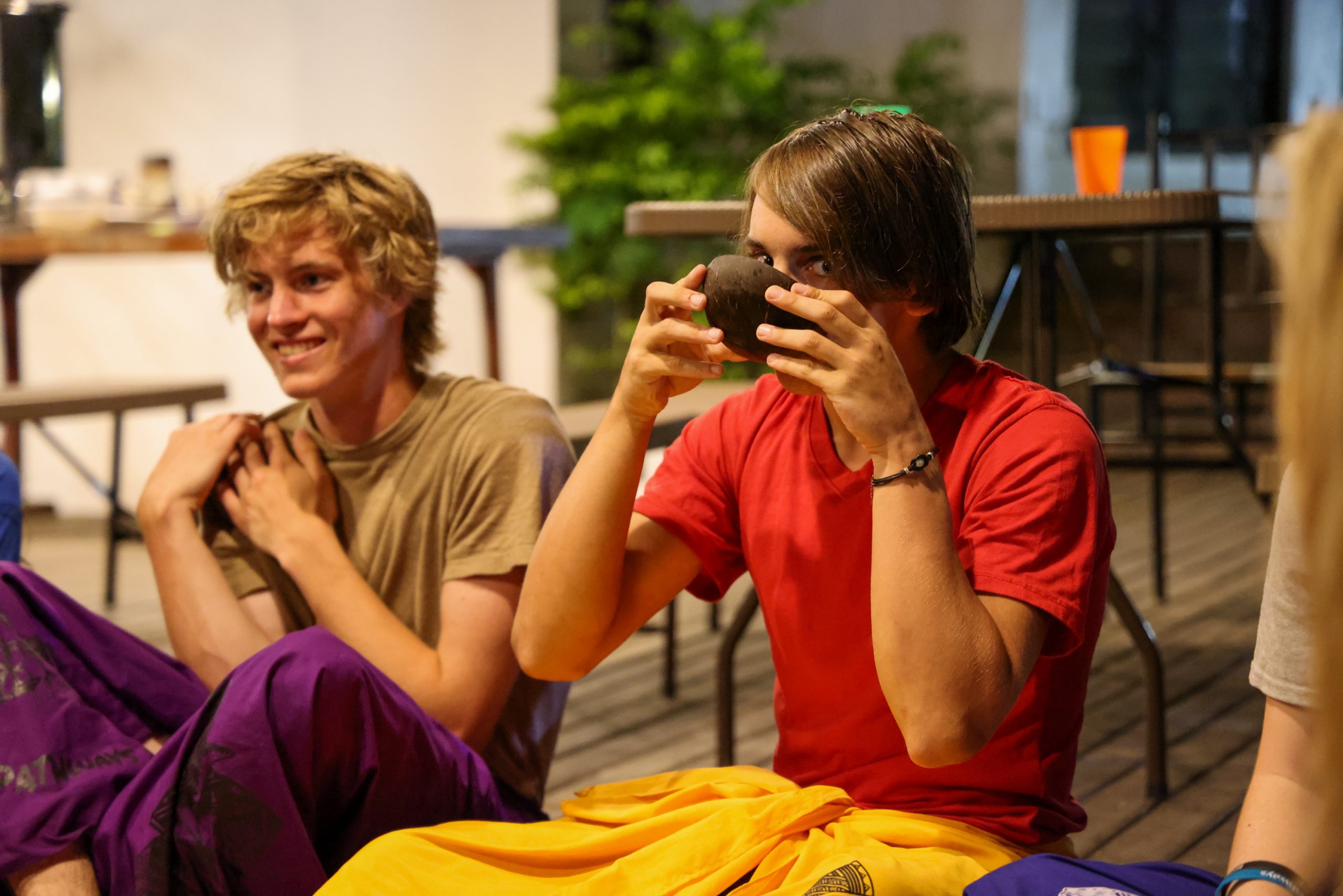 A student photographs the group with an instant camera during a relaxed indoor gathering