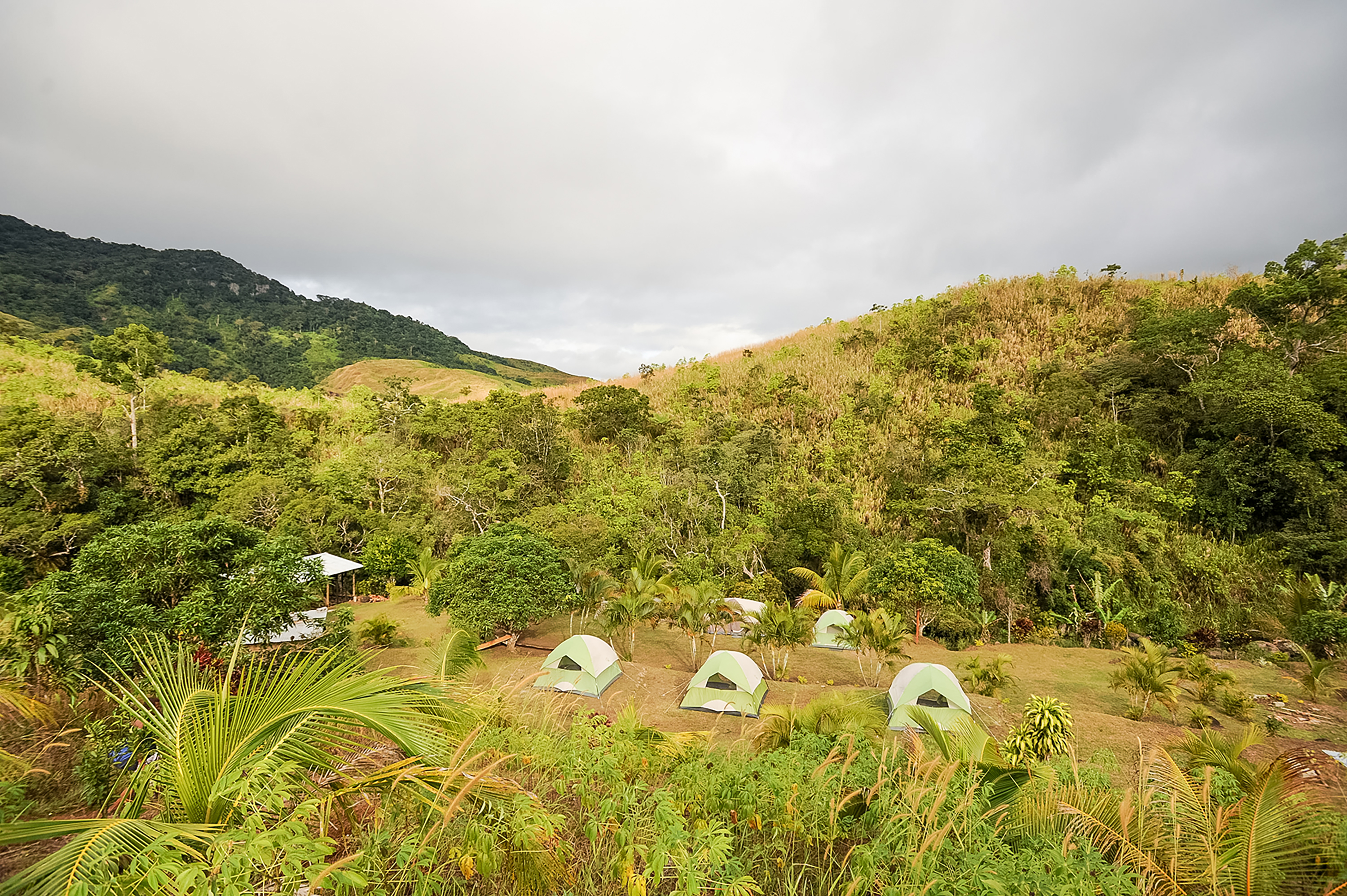 Tents set up in a clearing surrounded by lush, hilly terrain in Fiji