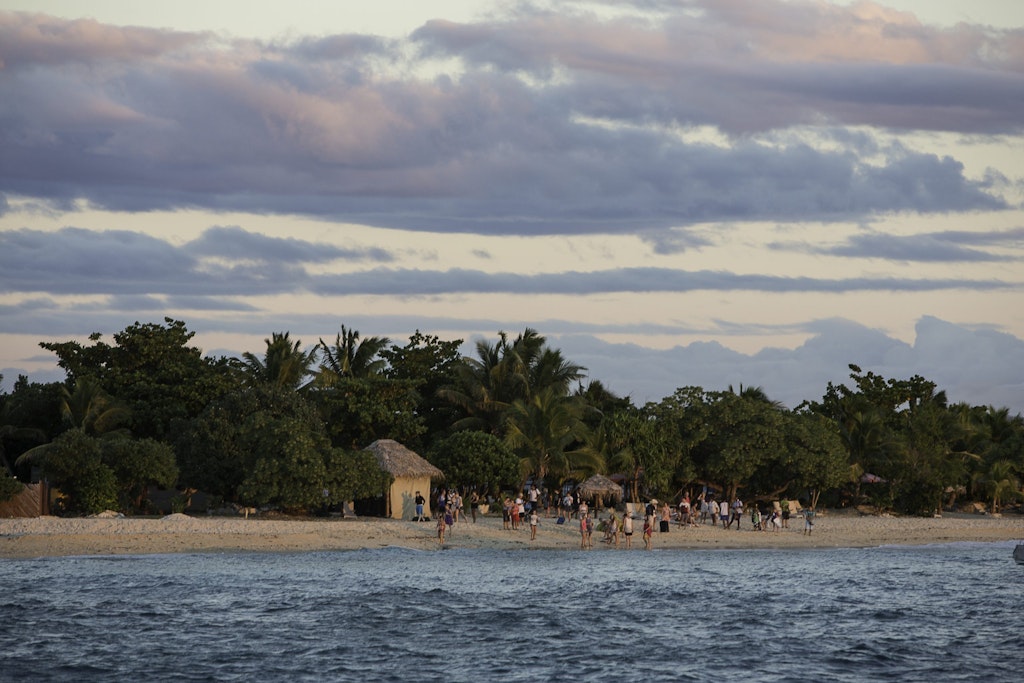 Students walking along a Fijian beach at sunset during a Rustic Pathways volunteer abroad in the Pacific program focused on community service and marine conservation.