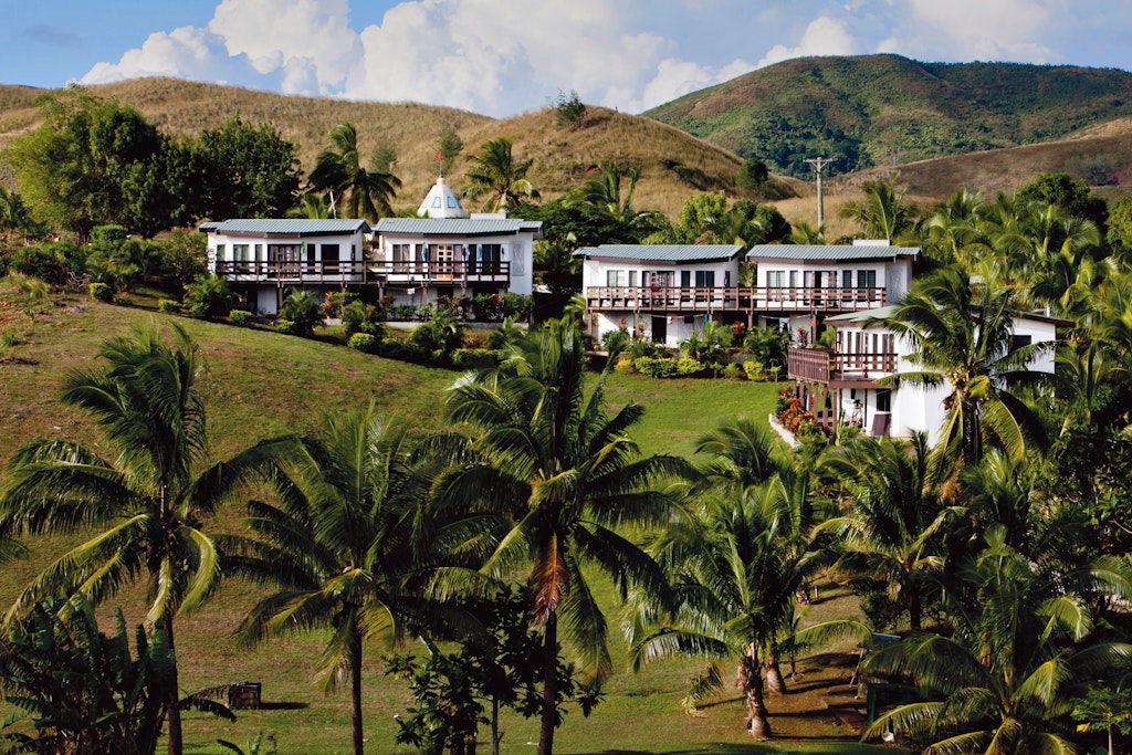 Rustic Pathways Eco-Lodge Service Base surrounded by palm trees and hills.