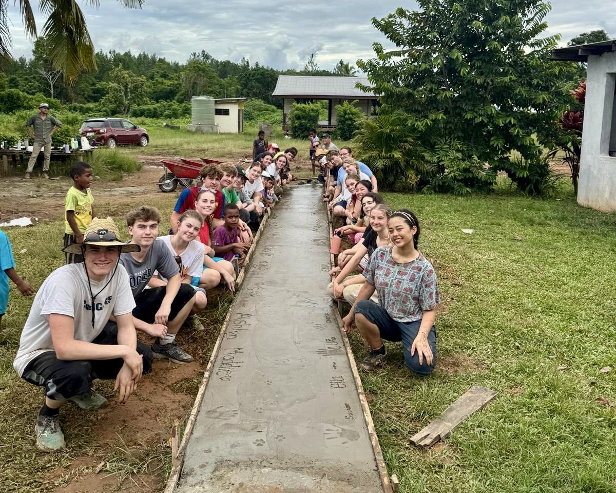 A school group lines the concrete path they laid in a Fijian village.