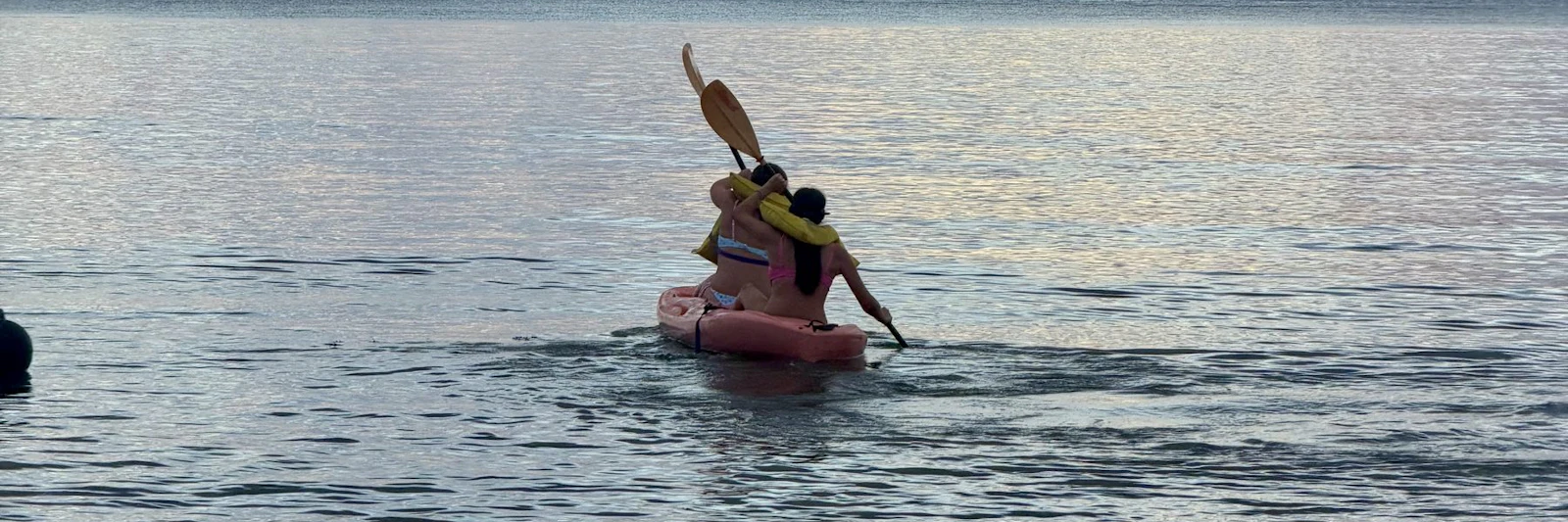 A kayaker paddles toward an island at sunset in Fiji.