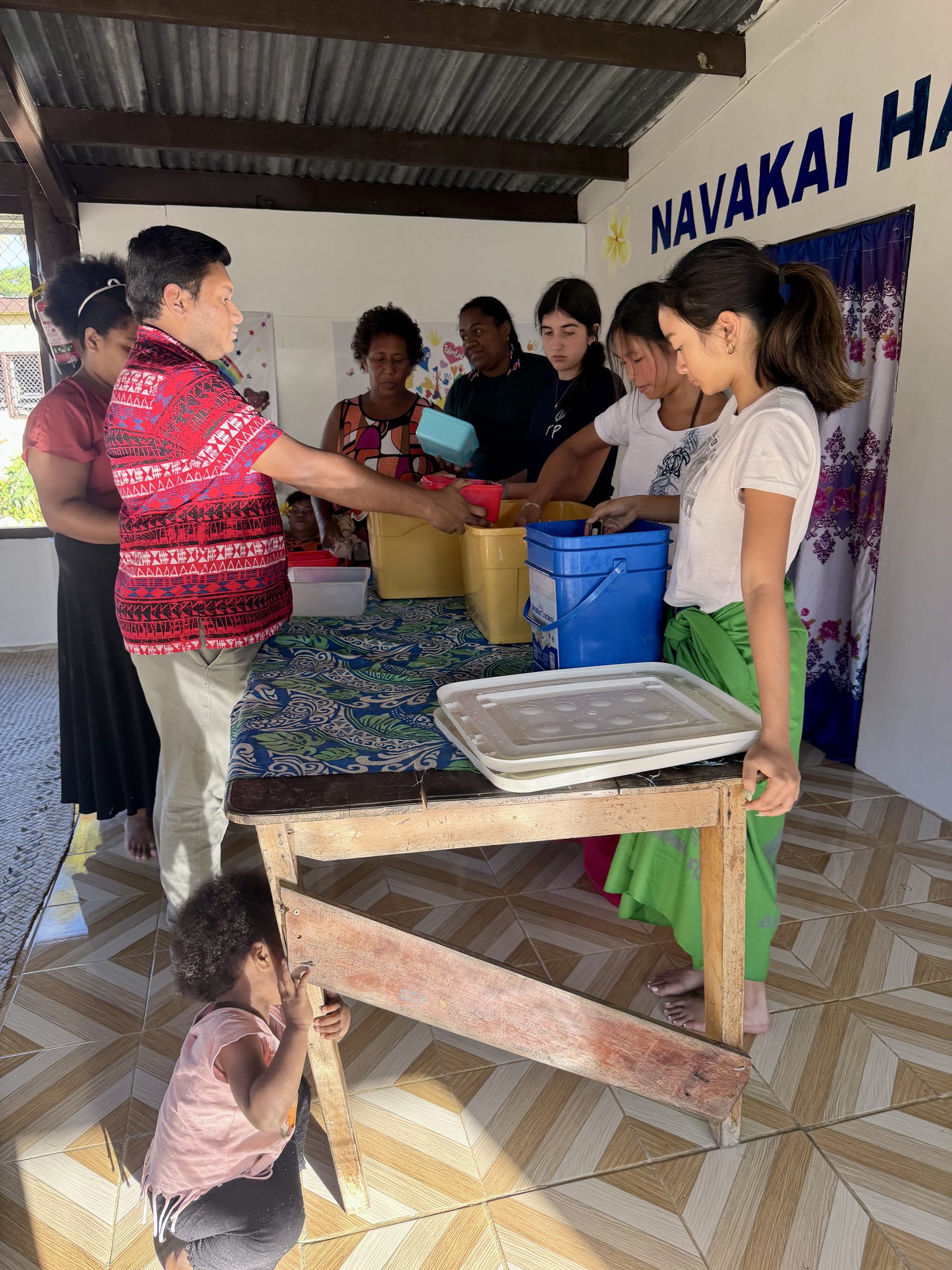 Students help prepare and serve food at a community house in Fiji.