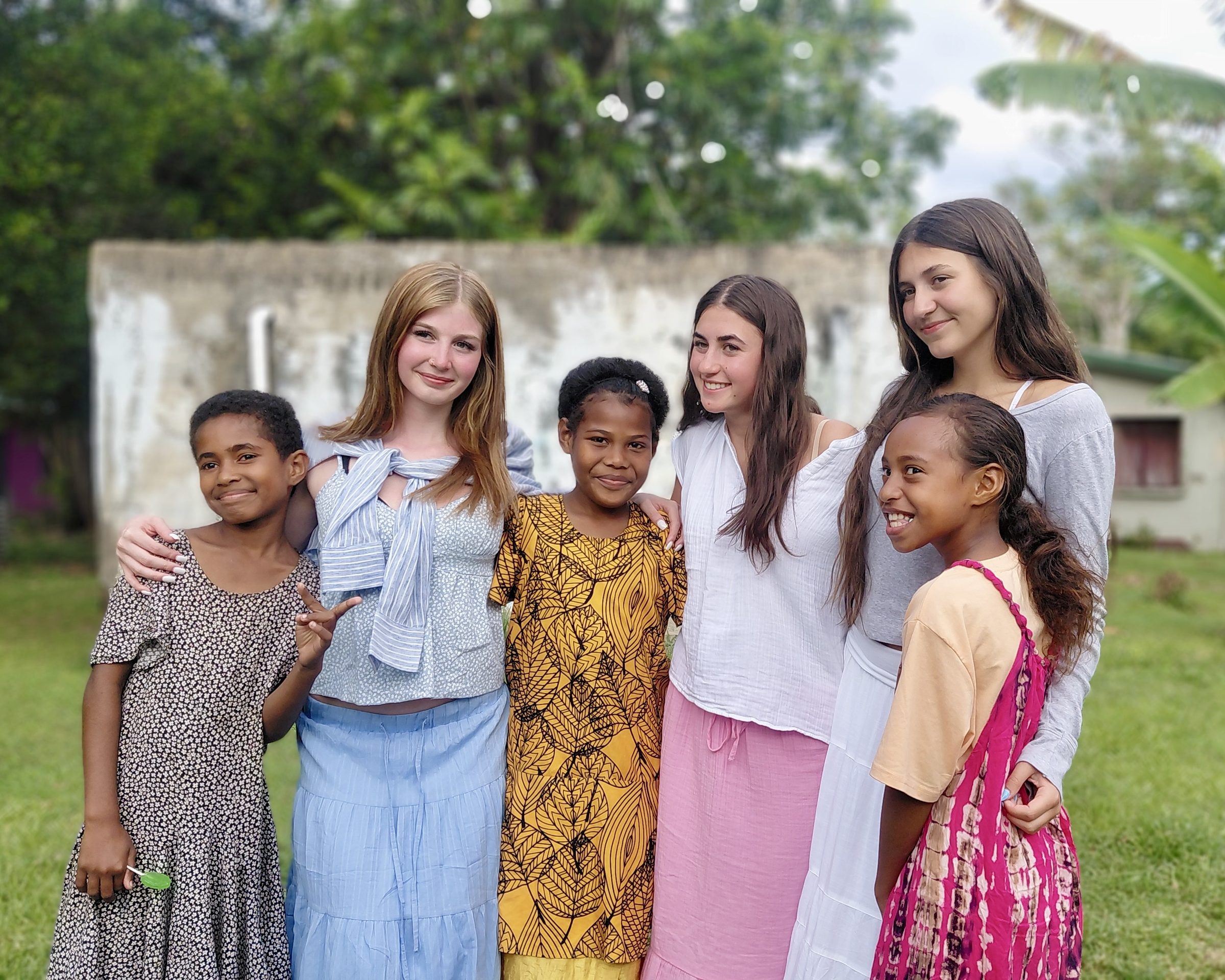 Students stand arm in arm with village girls outside a school in Fiji.