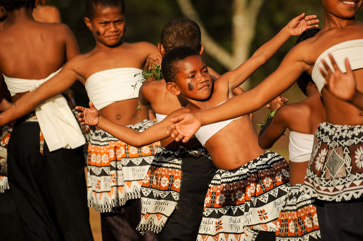 Dancers in traditional Fijian skirts perform with arms outstretched