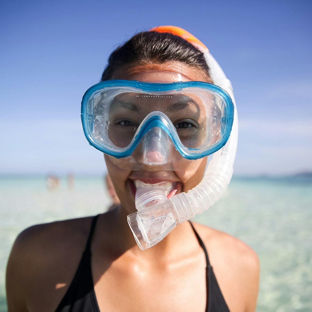 A girl in snorkeling gear smiles at the camera.