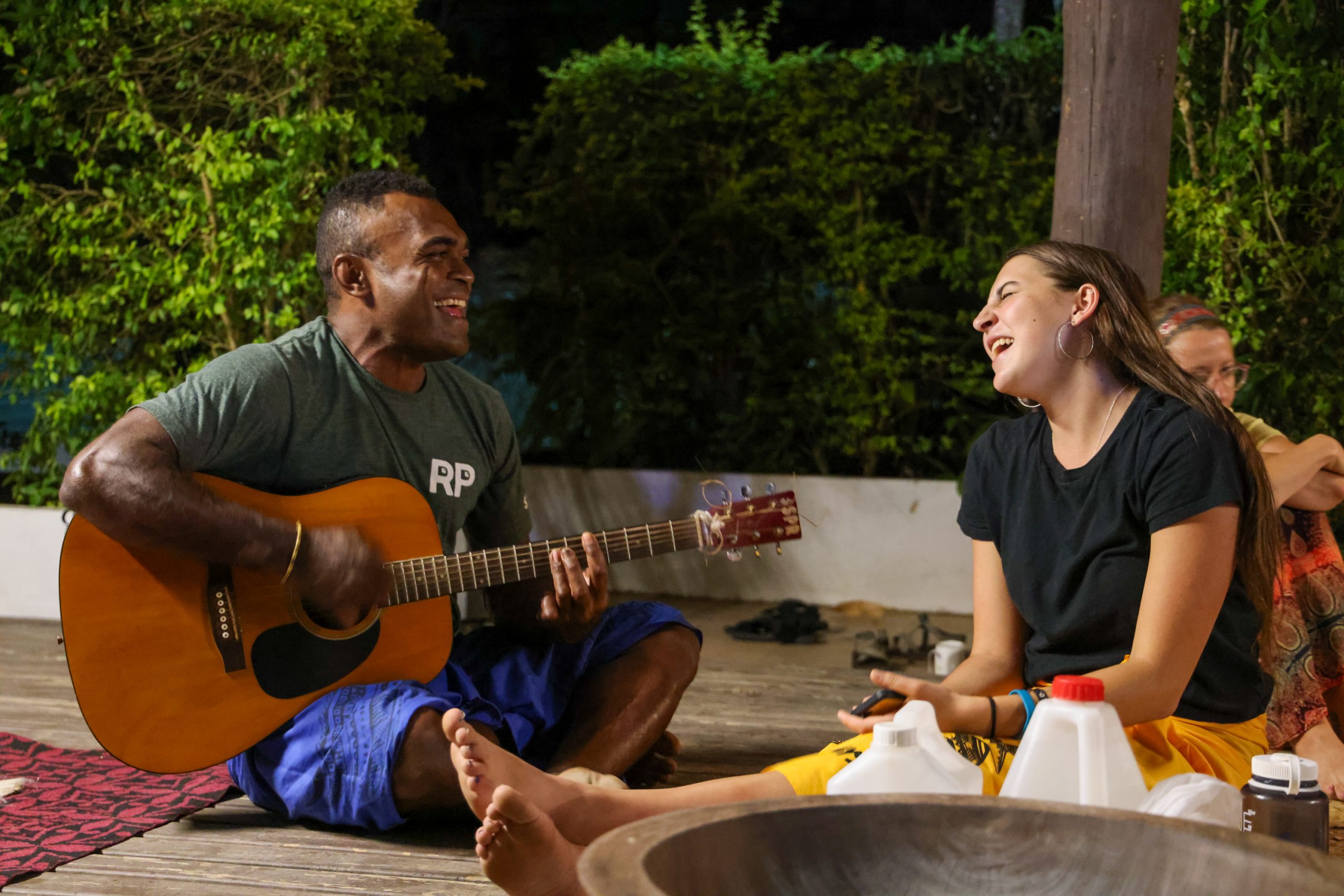A local musician plays guitar as a student laughs during an evening gathering