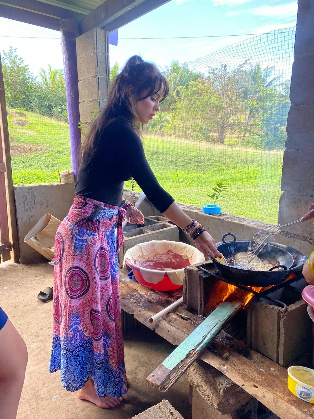 A woman cooks delicious local food with a great view of the green outdoors.