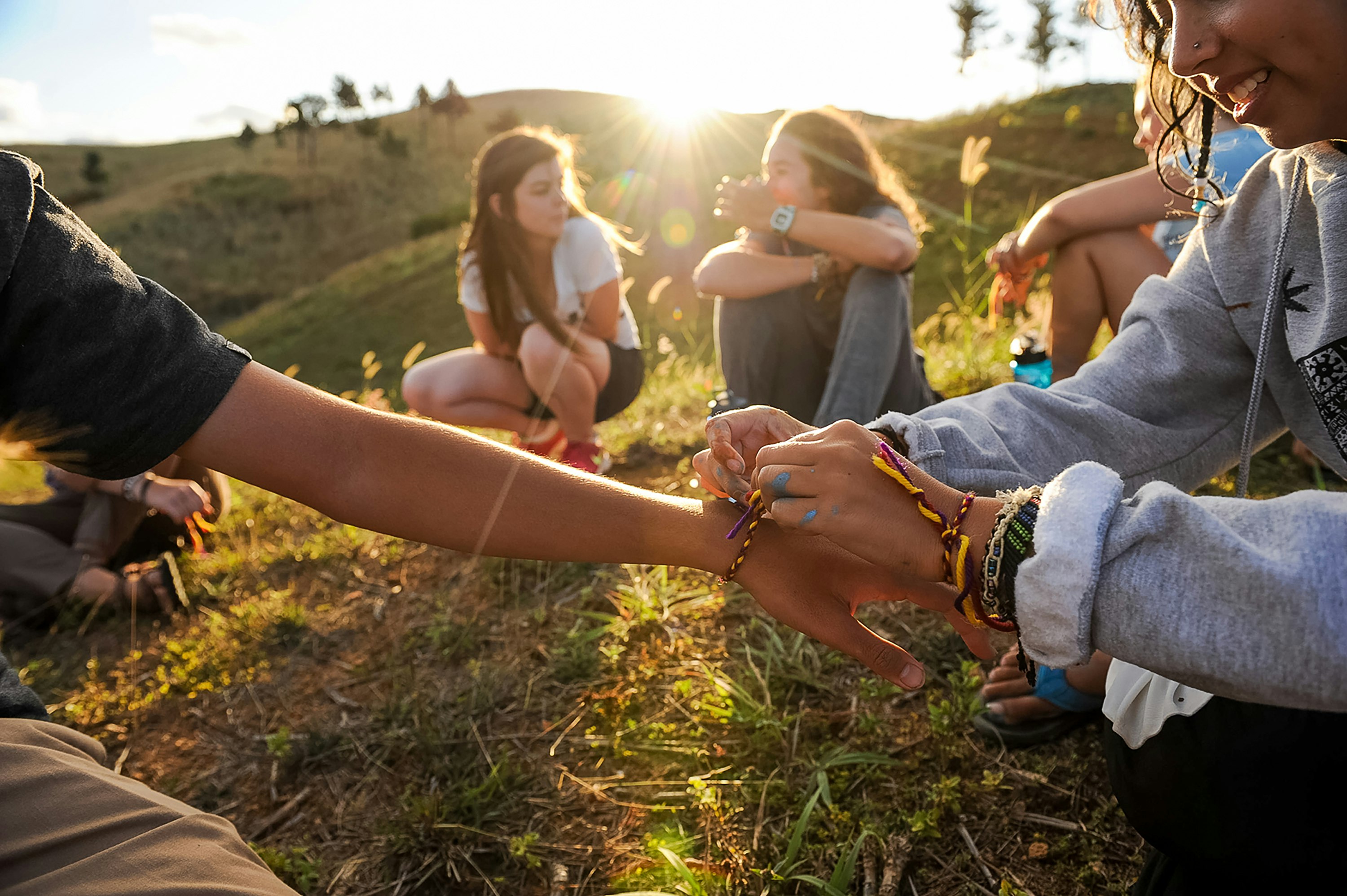 Students exchange handmade friendship bracelets outdoors.