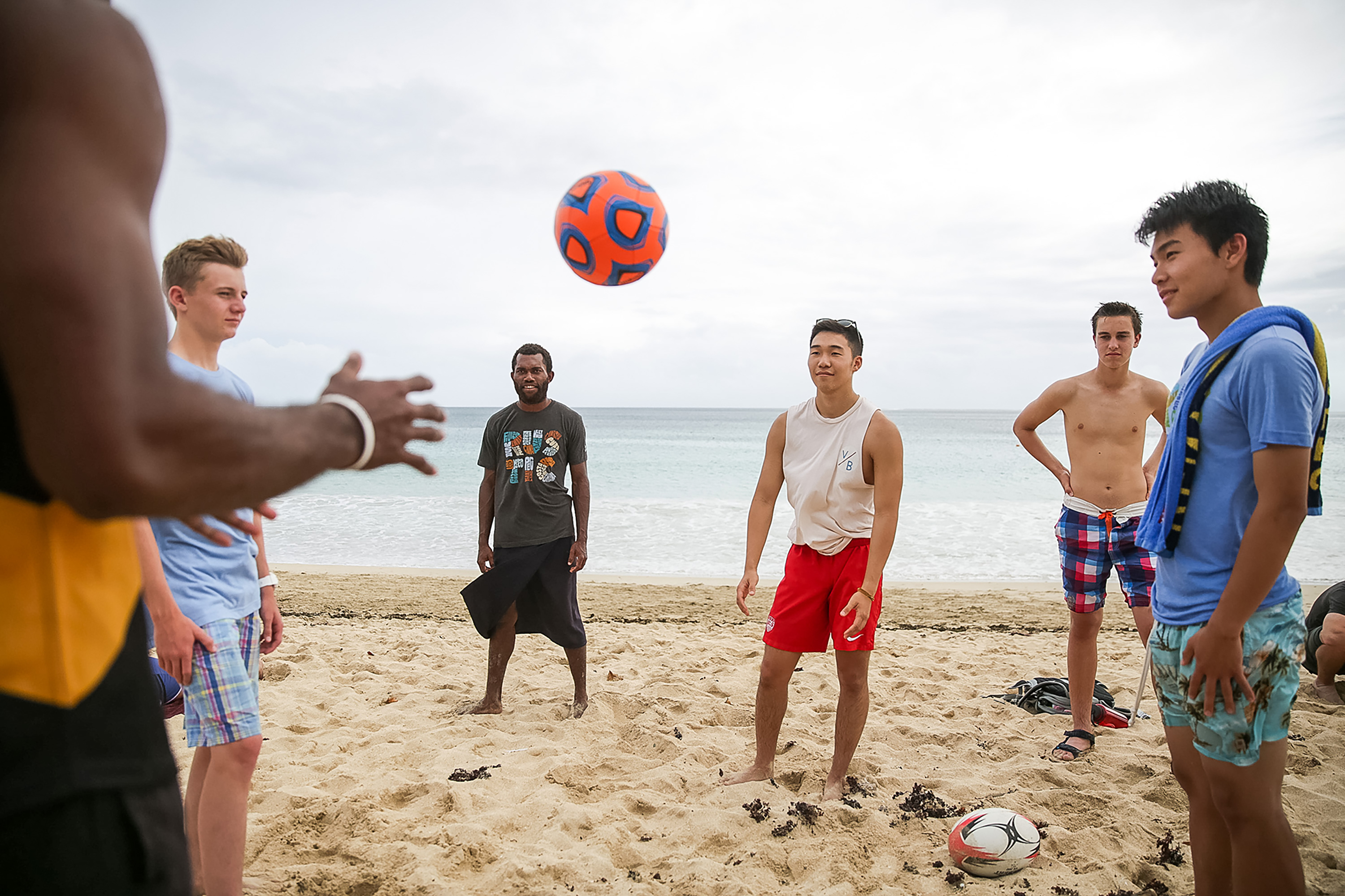 Students play with a ball on a beach