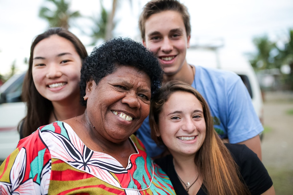 A diverse group of four is posing for a photo, having smiles all over their faces.