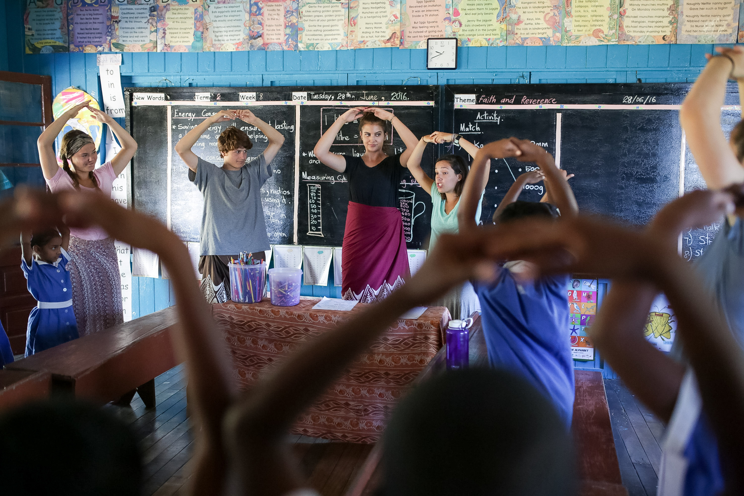 Students form triangle shapes with their arms during a classroom activity