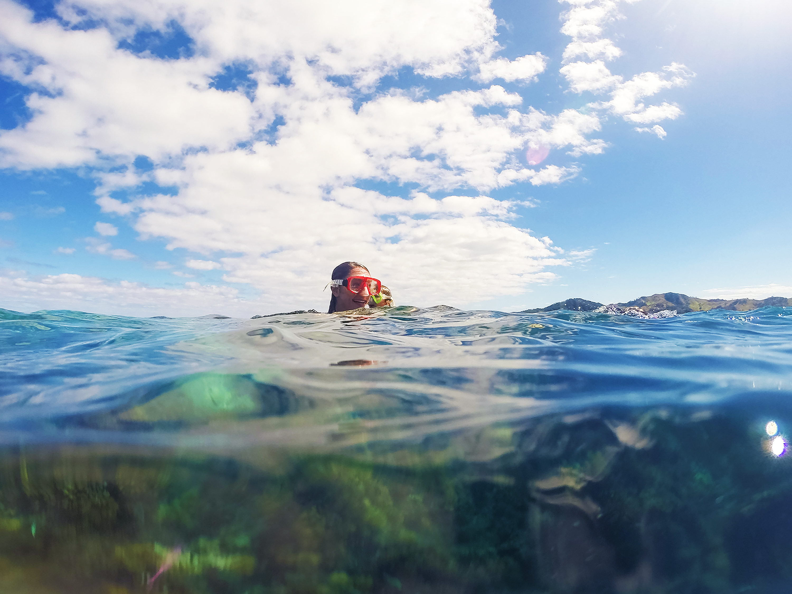 A student wearing a snorkel mask floats at the surface above a reef