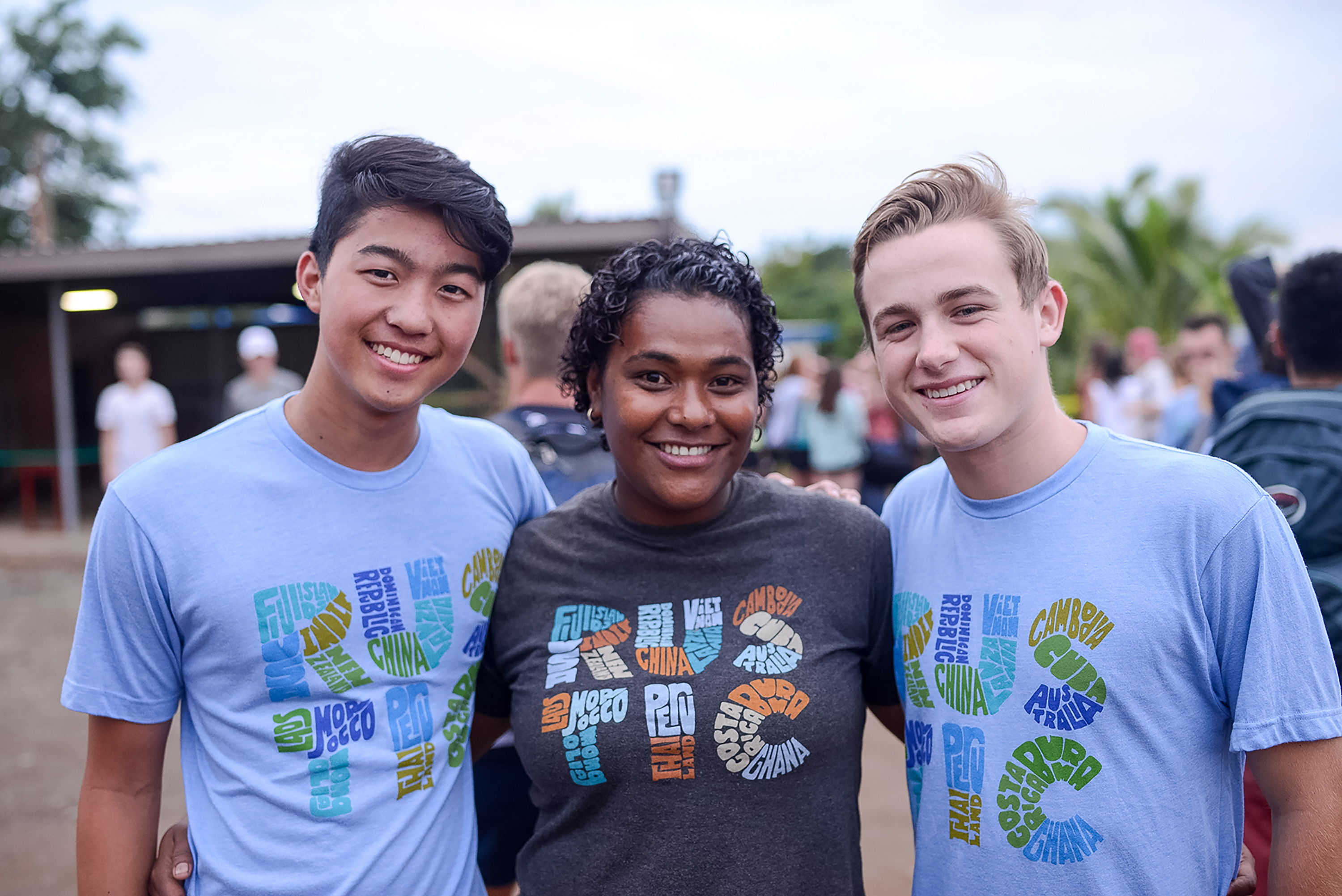 Students smile together arm in arm at an outdoor gathering