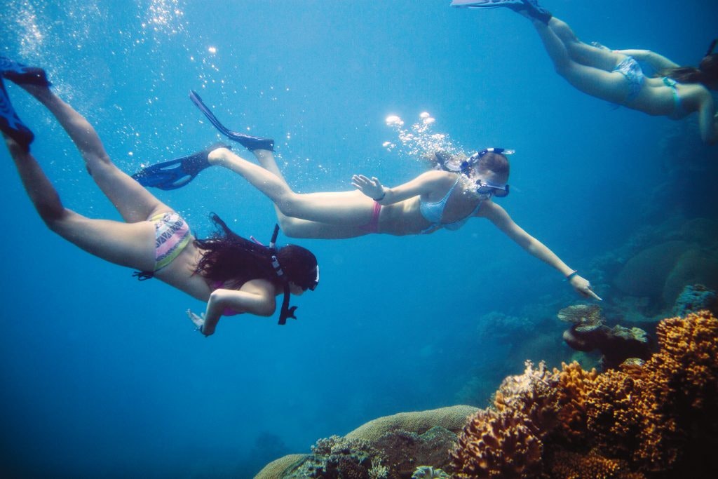 A student points something out to her friend while snorkeling on a teen tour in oceania