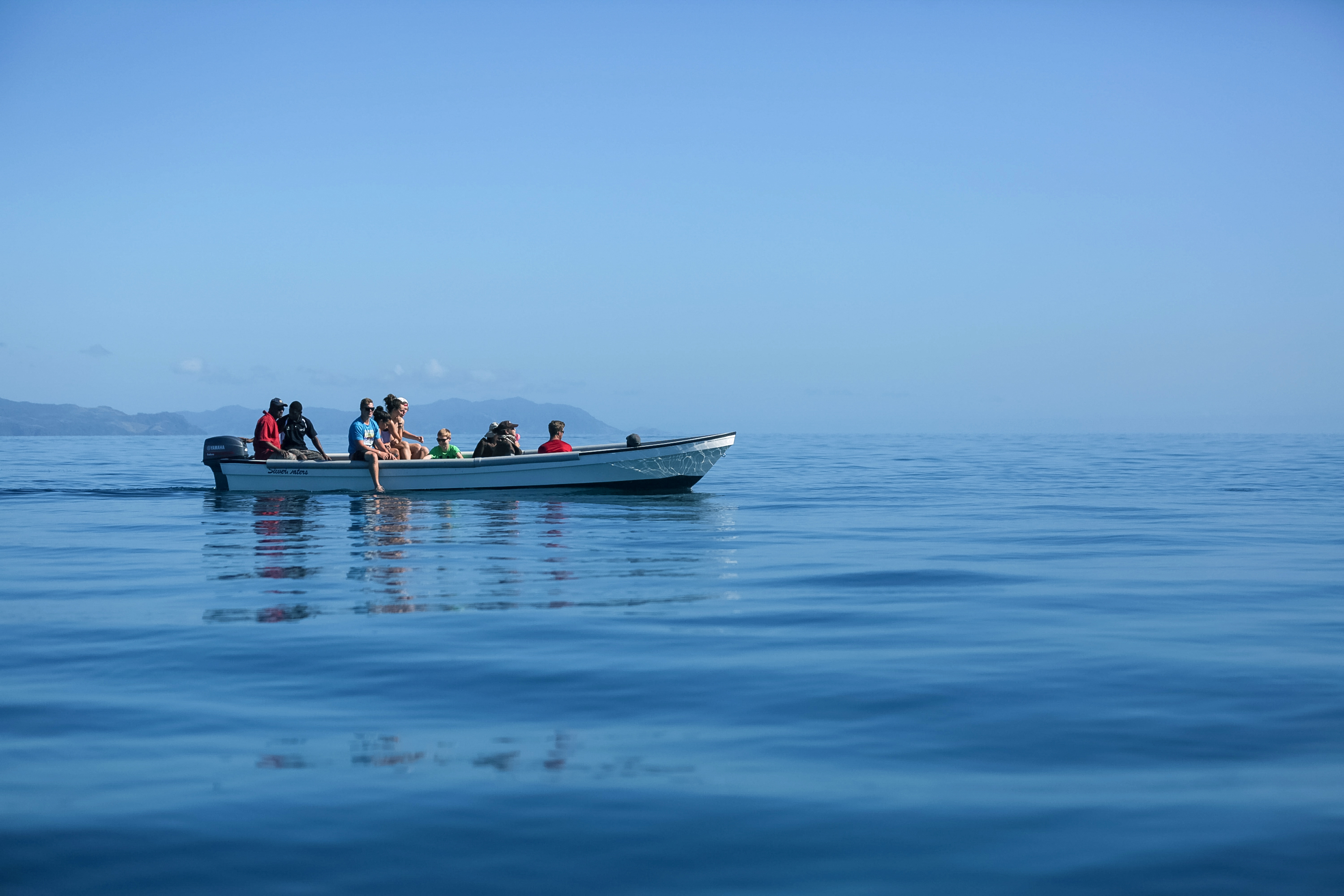 Students ride a small boat across calm open water