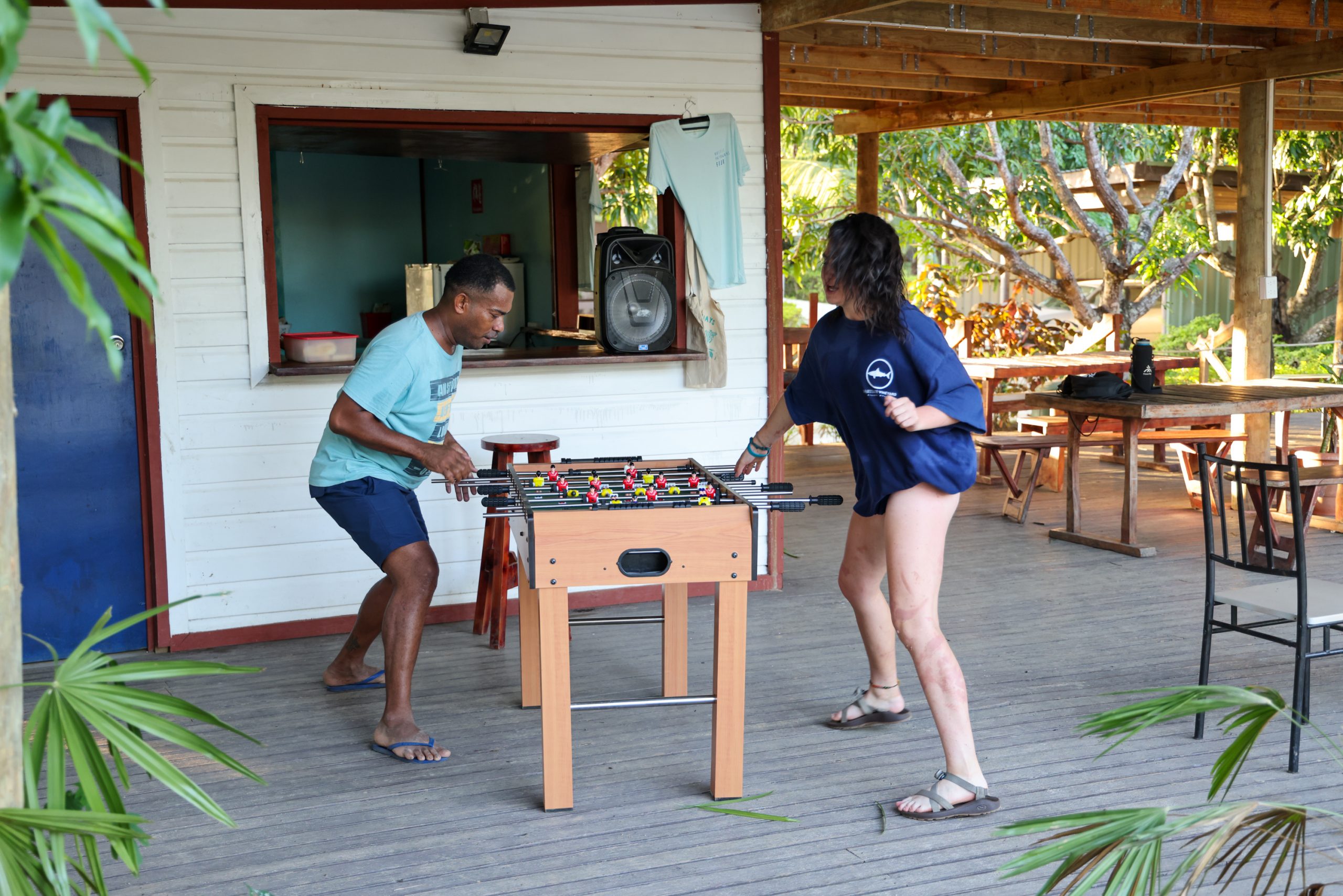 Students play foosball on a covered wooden deck