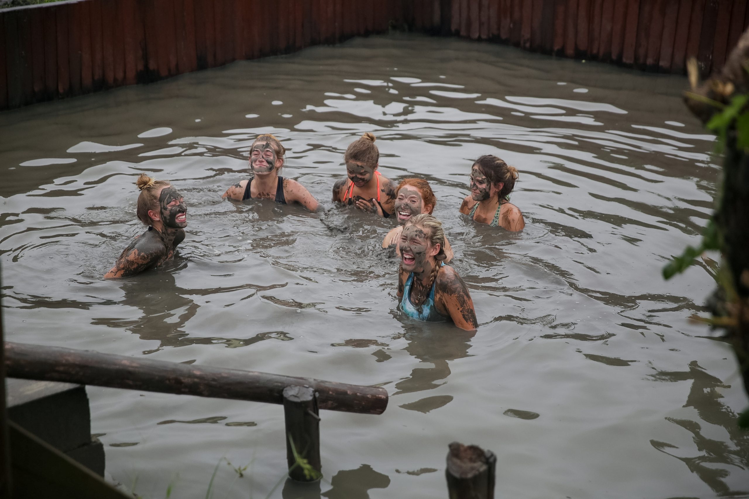Students covered in mud laugh together in a muddy pool