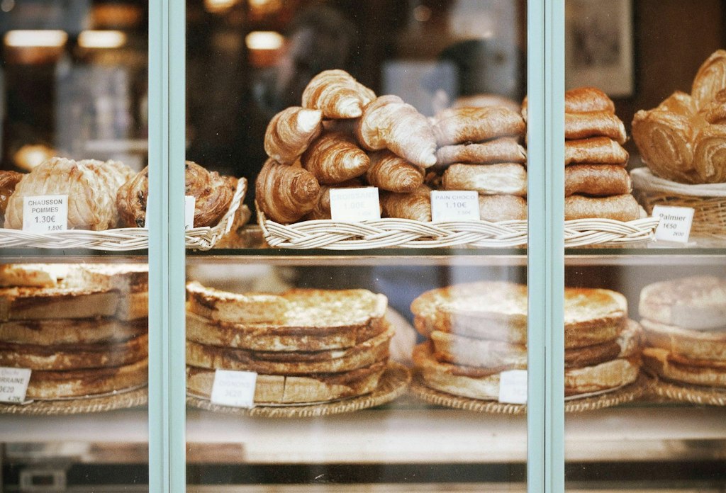 The bakery window is filled with warm, flaky croissants and other French baked goods.