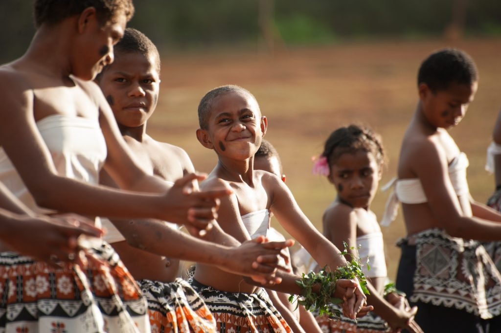 Young Fijian boys in traditional attire preparing for a cultural dance