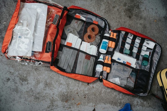 Basic first aid kit lying on the floor, opened with a tri-fold.