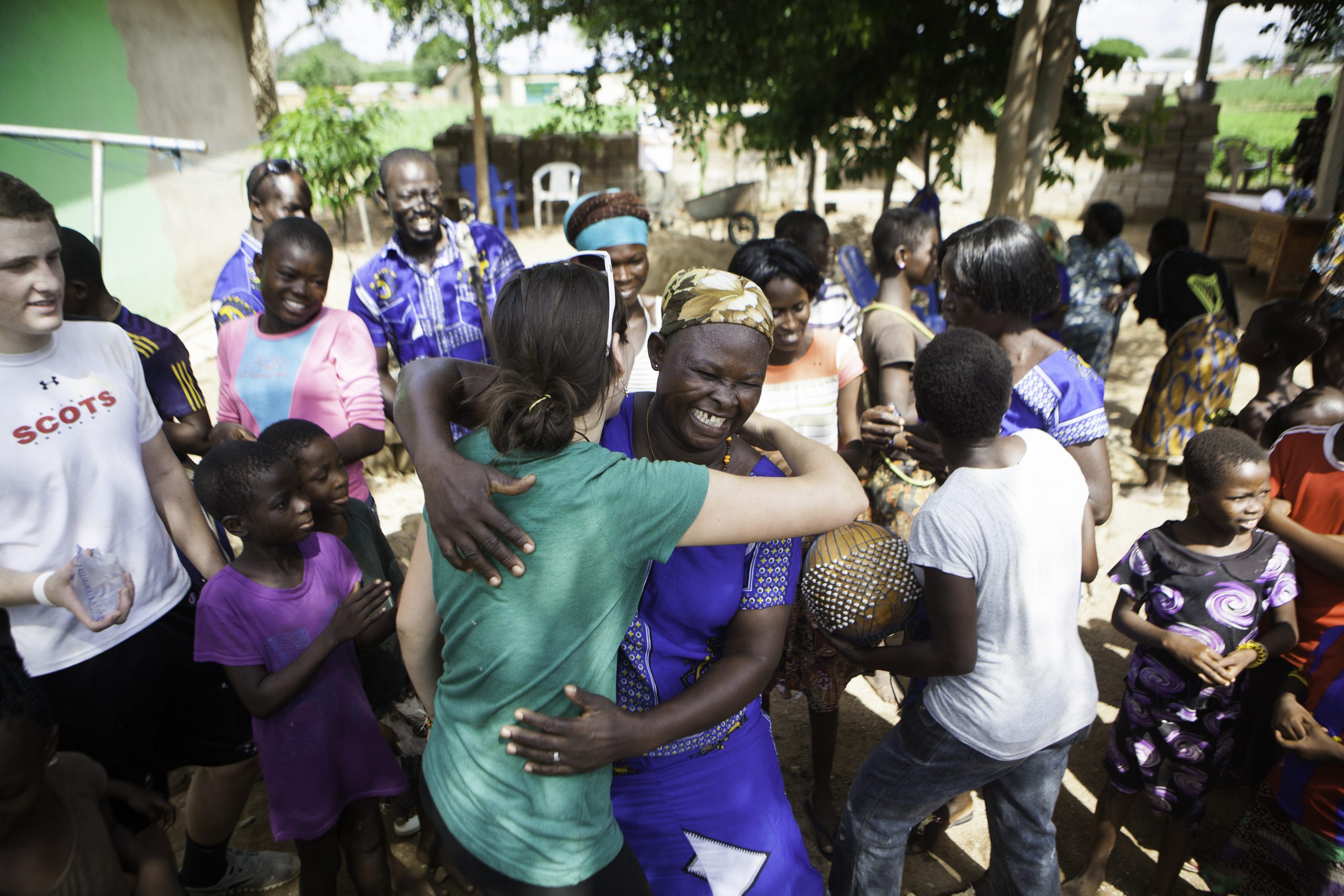 A student embraces a local woman as community members gather around