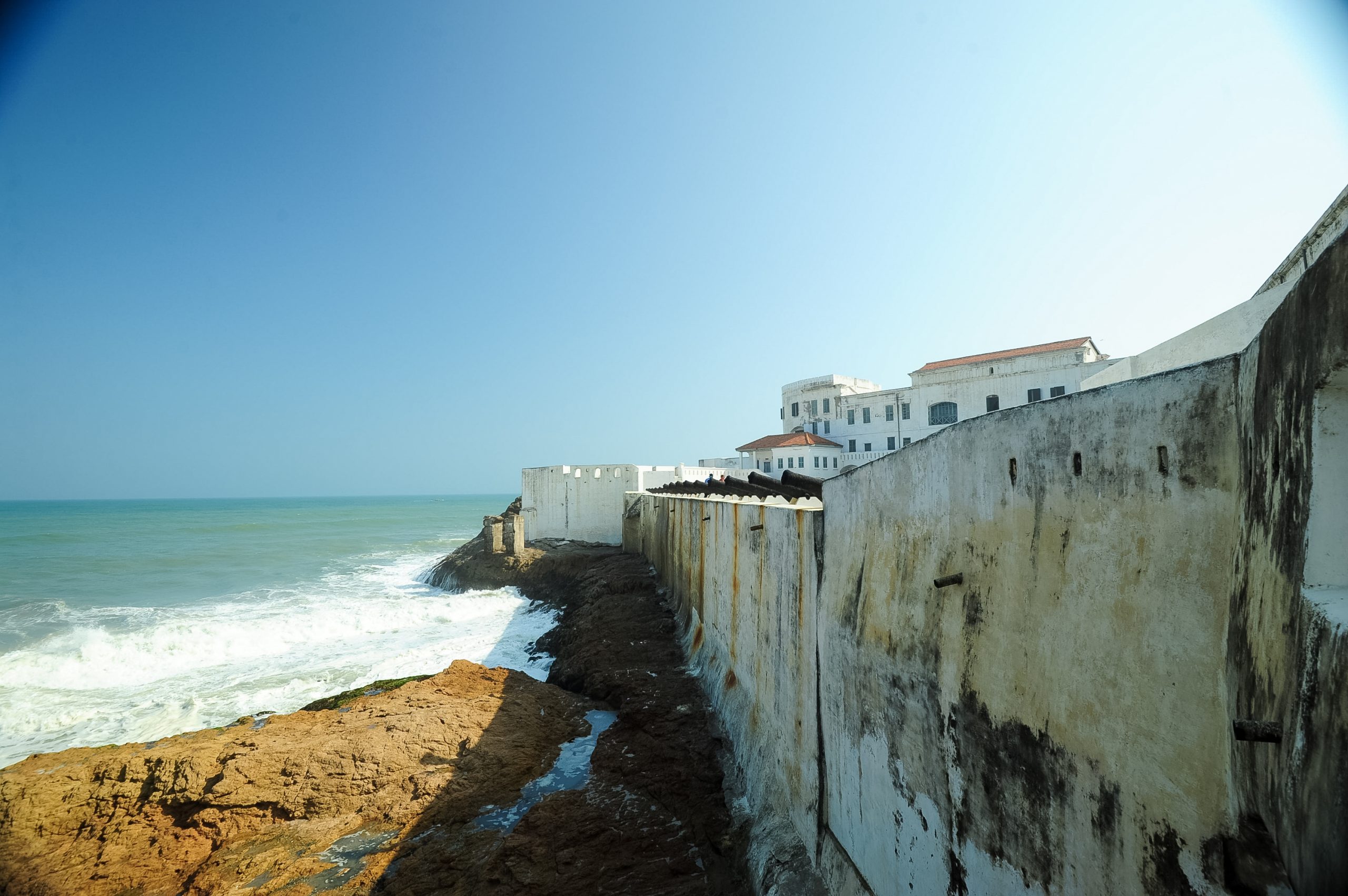 Weathered coastal fort walls line a cliff above crashing waves