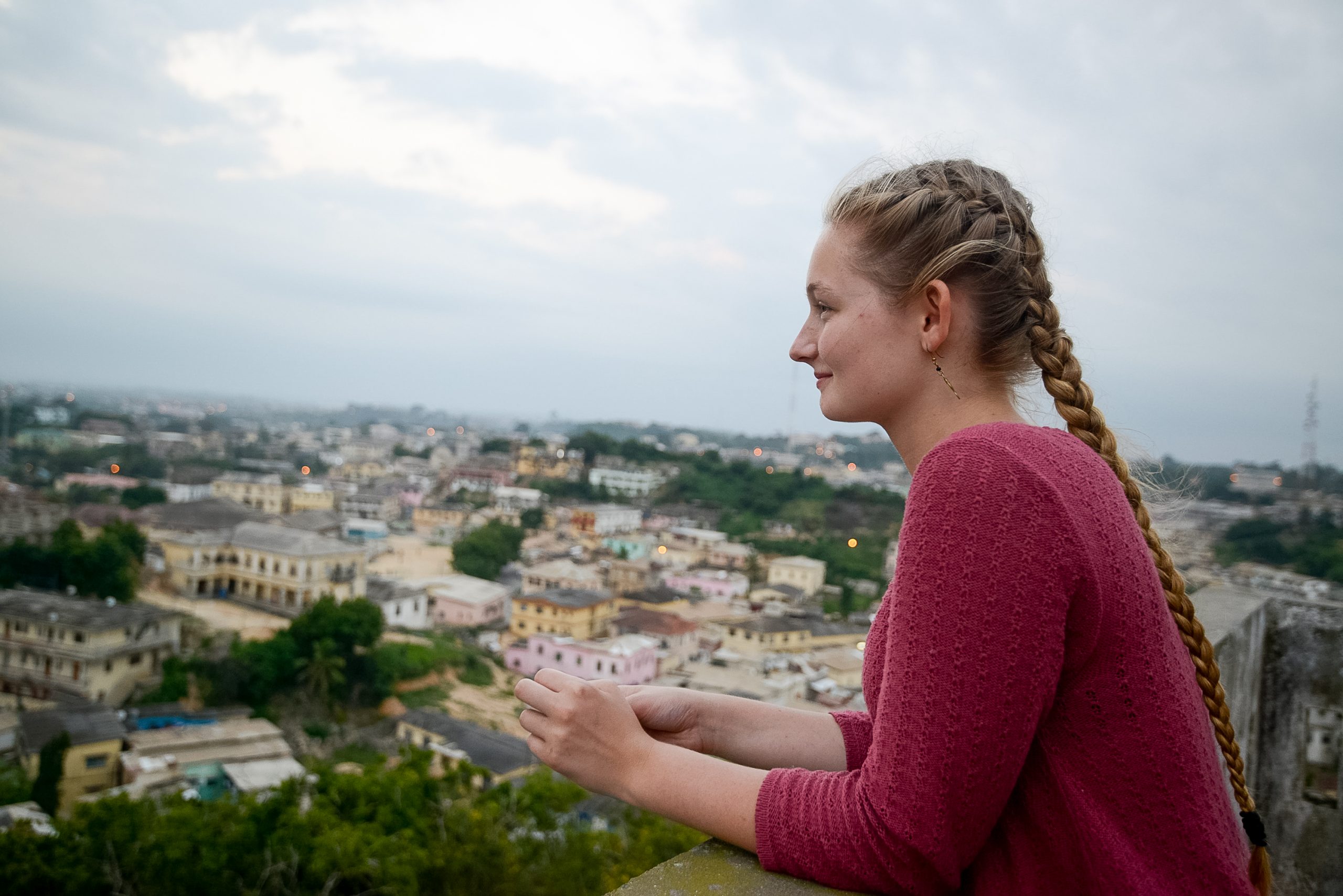 A student looks out over a hillside town under an overcast sky