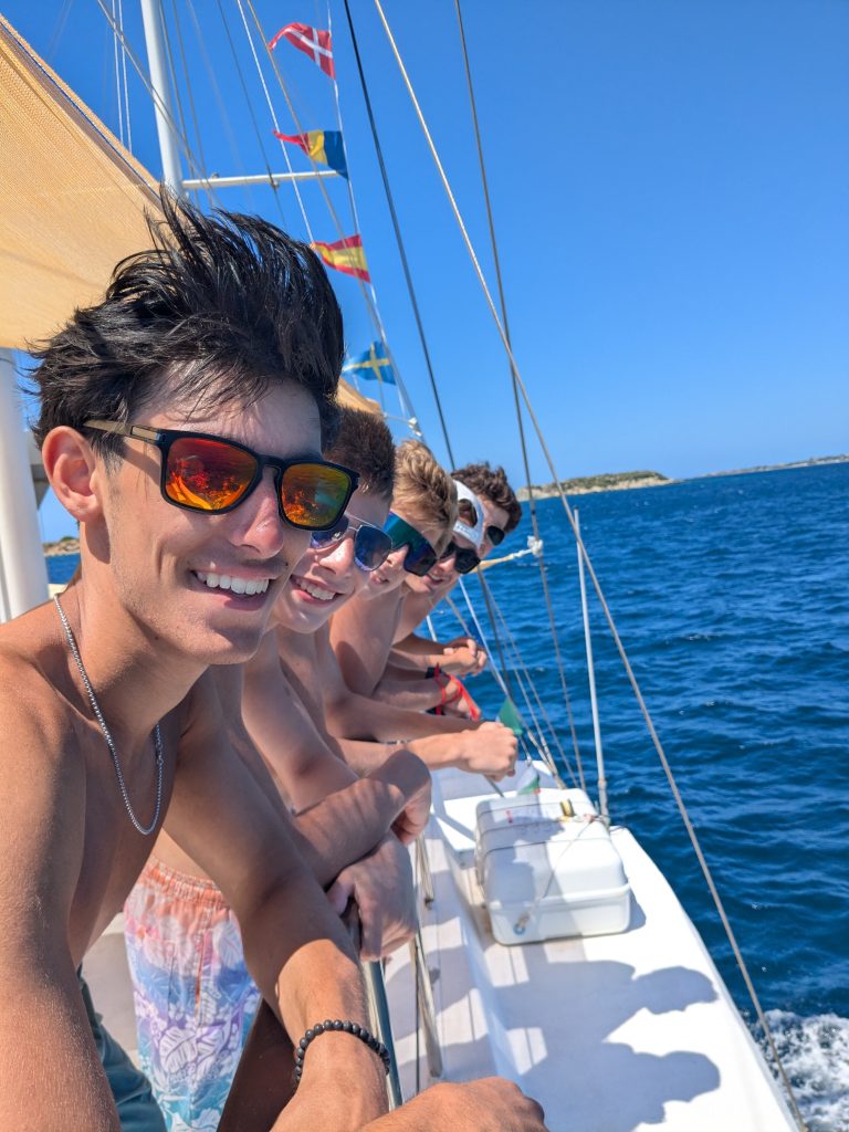 Students smiling on a boat trip during a Rustic Pathways teen tour in Italy and Greece.