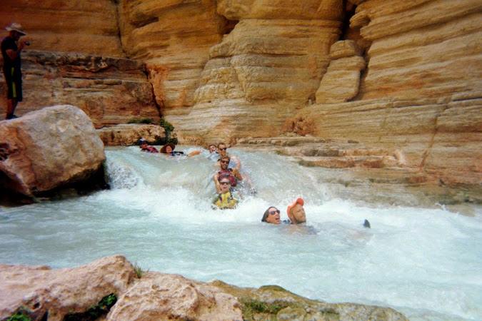 Students float through churning water in a rocky canyon pool