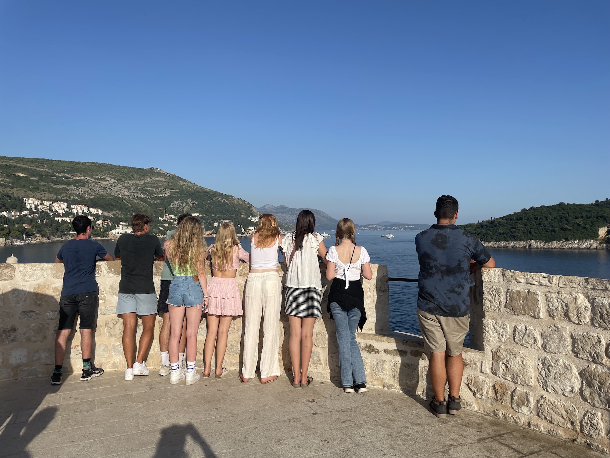 A group of students looks out from Dubrovnik's city walls over the Adriatic coastline.