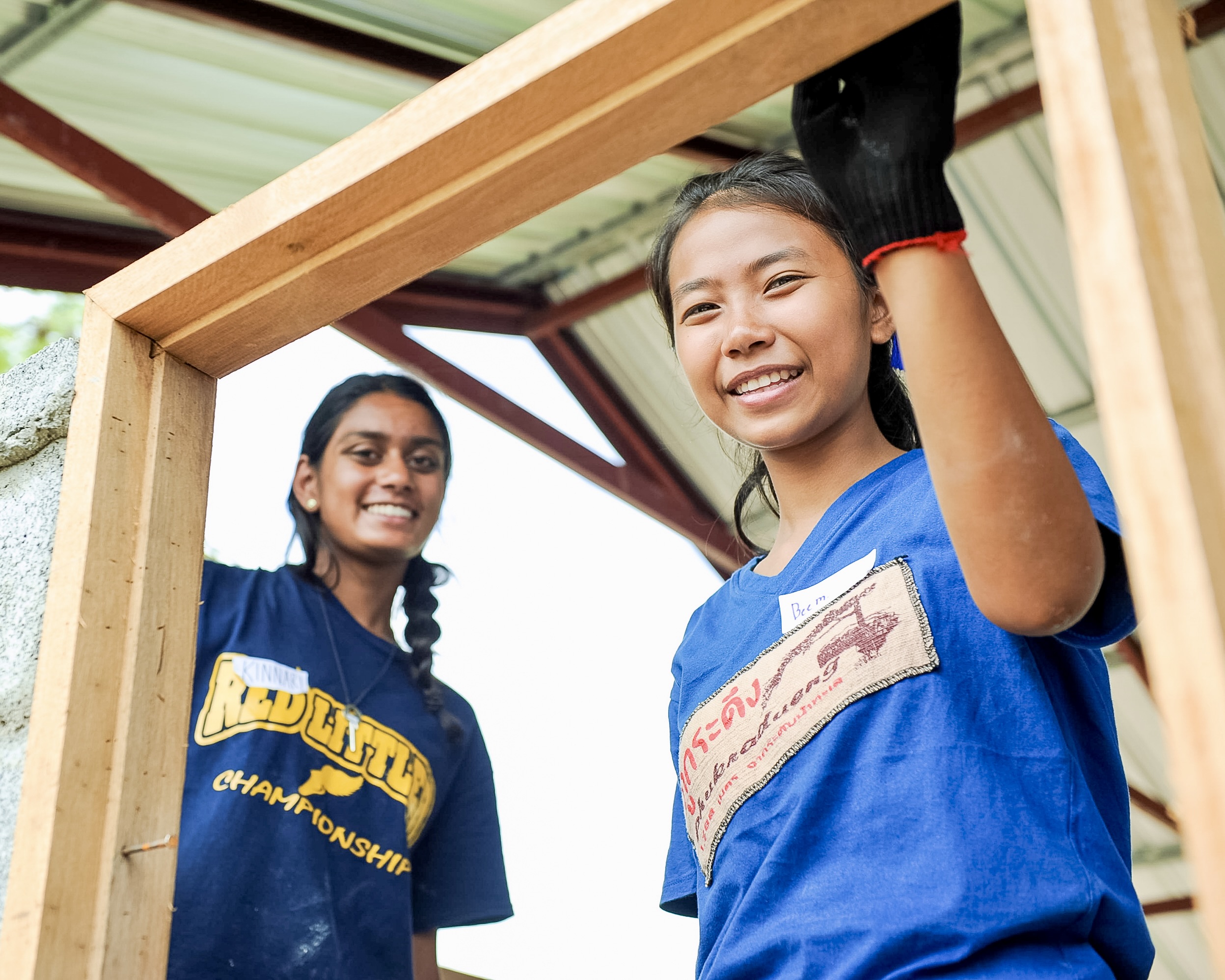 Two high school volunteers building a wooden structure, learning teamwork and leadership on a Summer Volunteer Program Abroad.