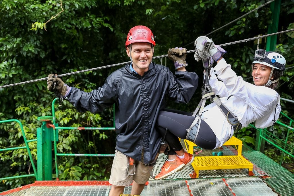 A subcontractor getting a student ready to go on a zipline on an outdoor program.