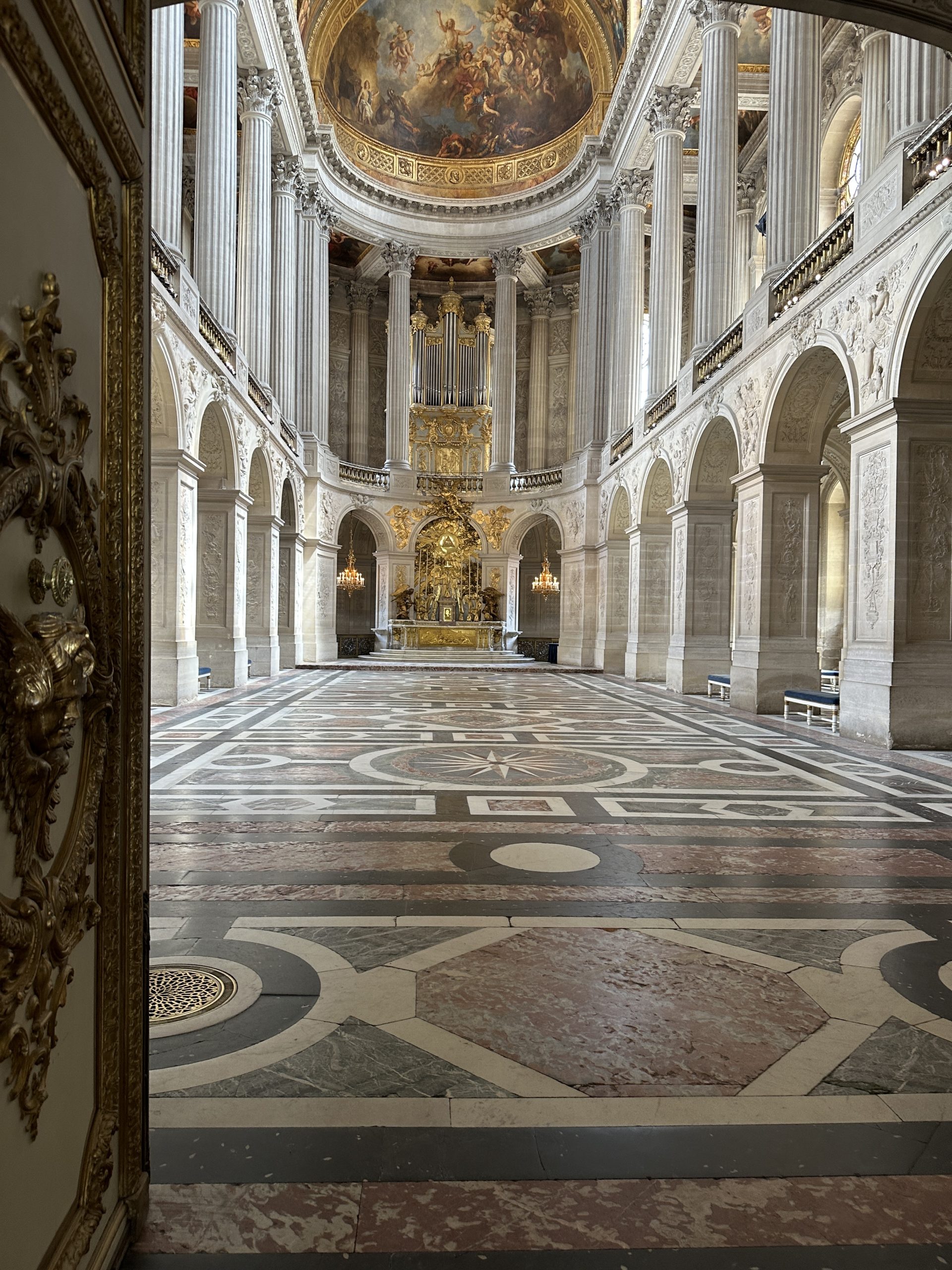 Lavish interior of the Palace of Versailles Chapel with grand columns and intricate floor design