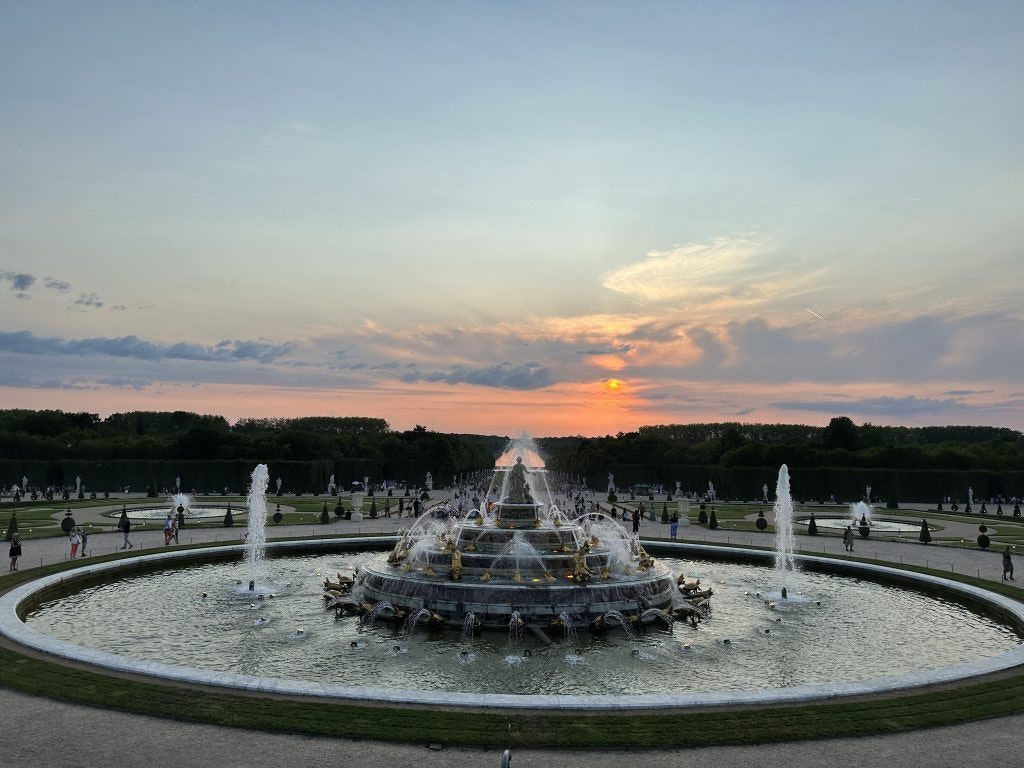 Fountain at the Palace of Versailles during sunset with people in the background
