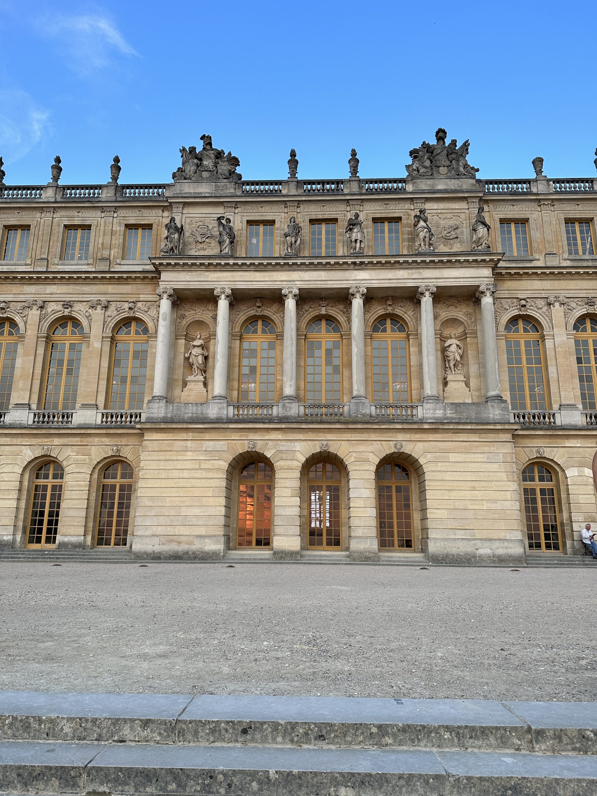 Exterior view of the Palace of Versailles featuring classical architecture and statues