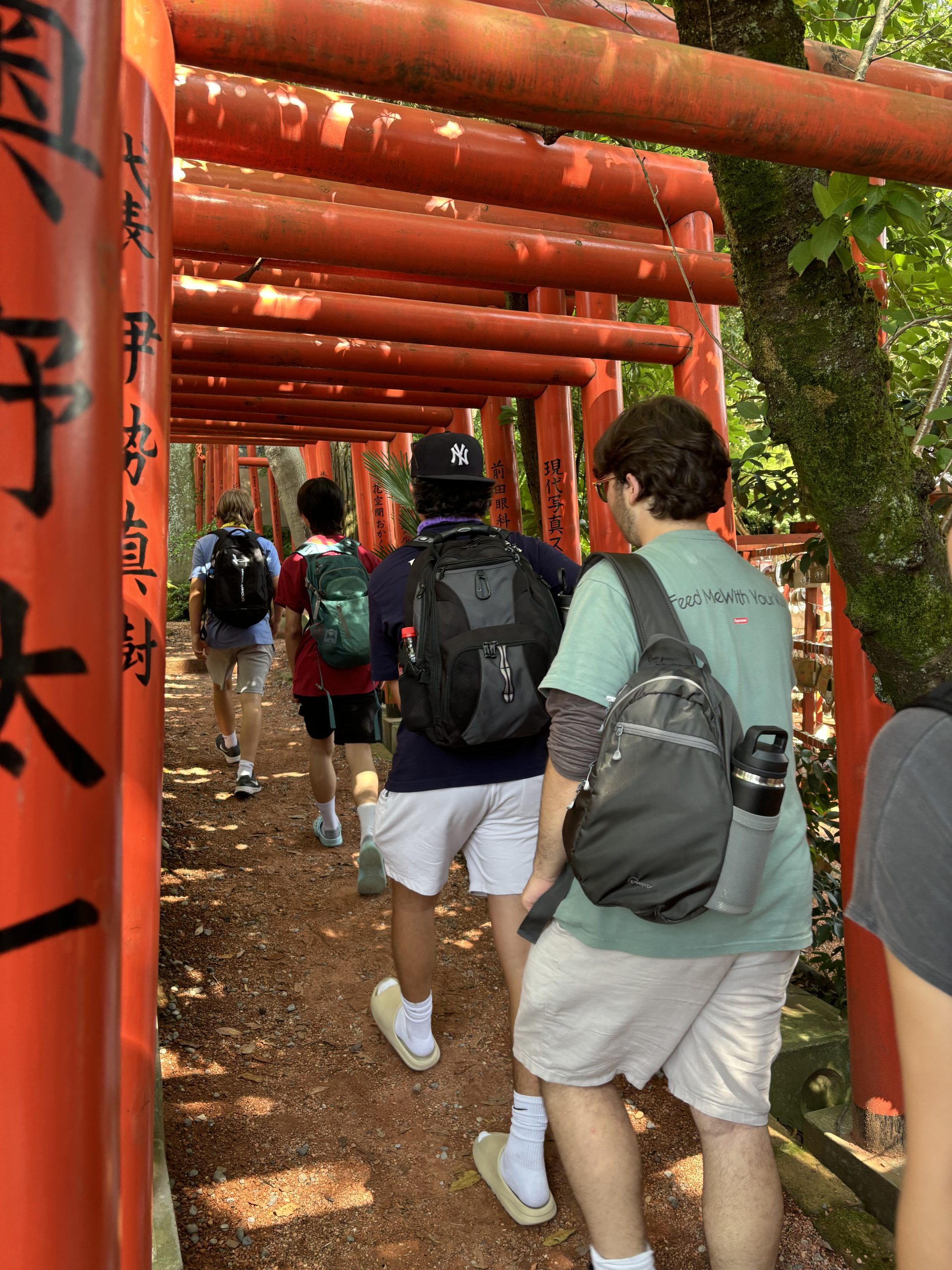 Students walk beneath a tunnel of red torii gates in Japan