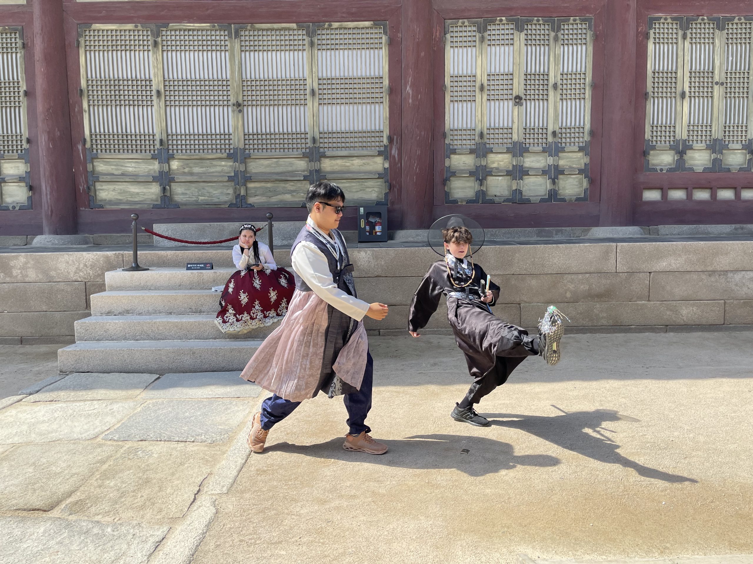 A student and tour guide play a traditional Korean game in the middle of a Korean palace.