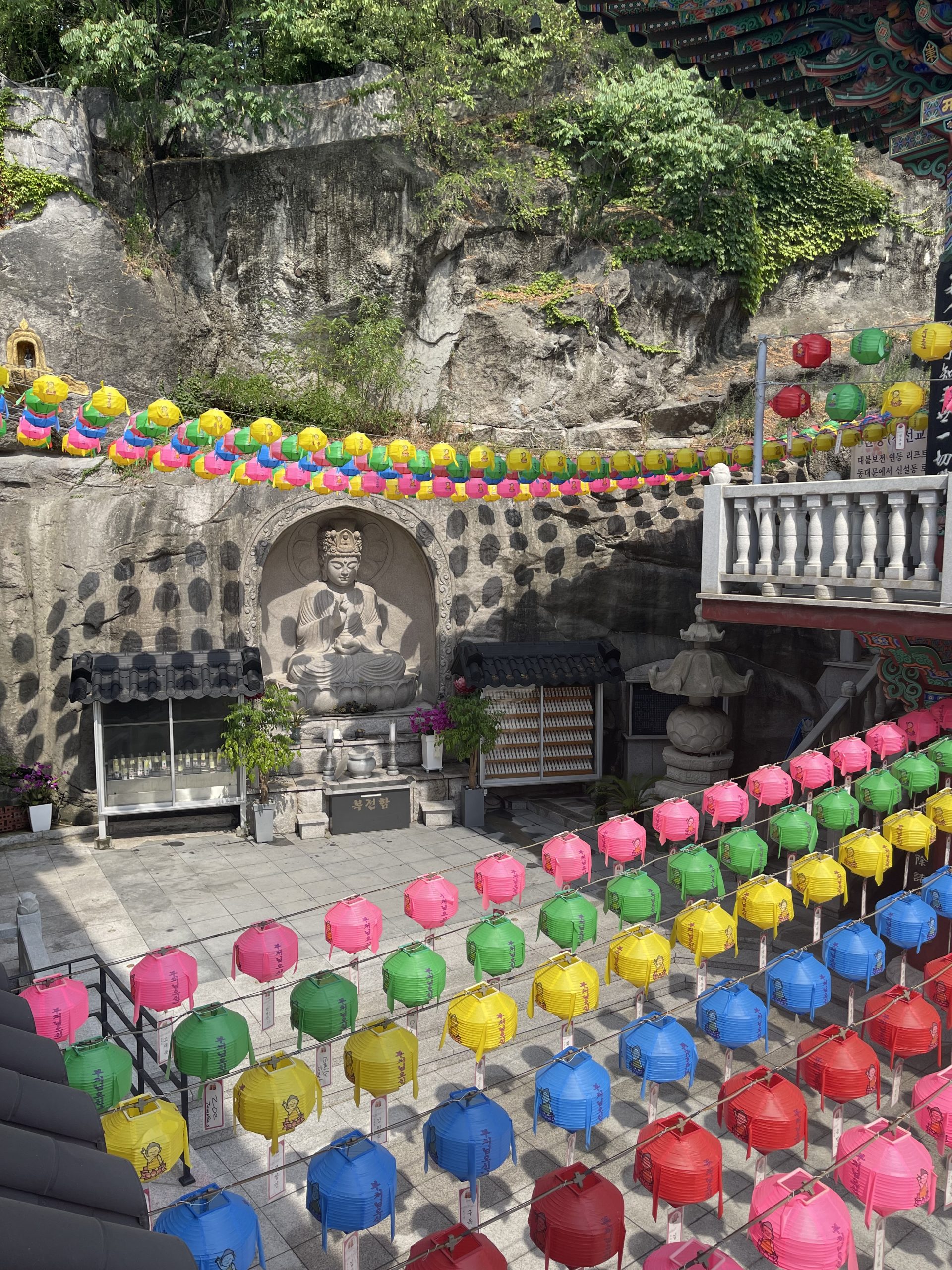 Multicolored lanters hang over a courtyard at a Buddhist temple.
