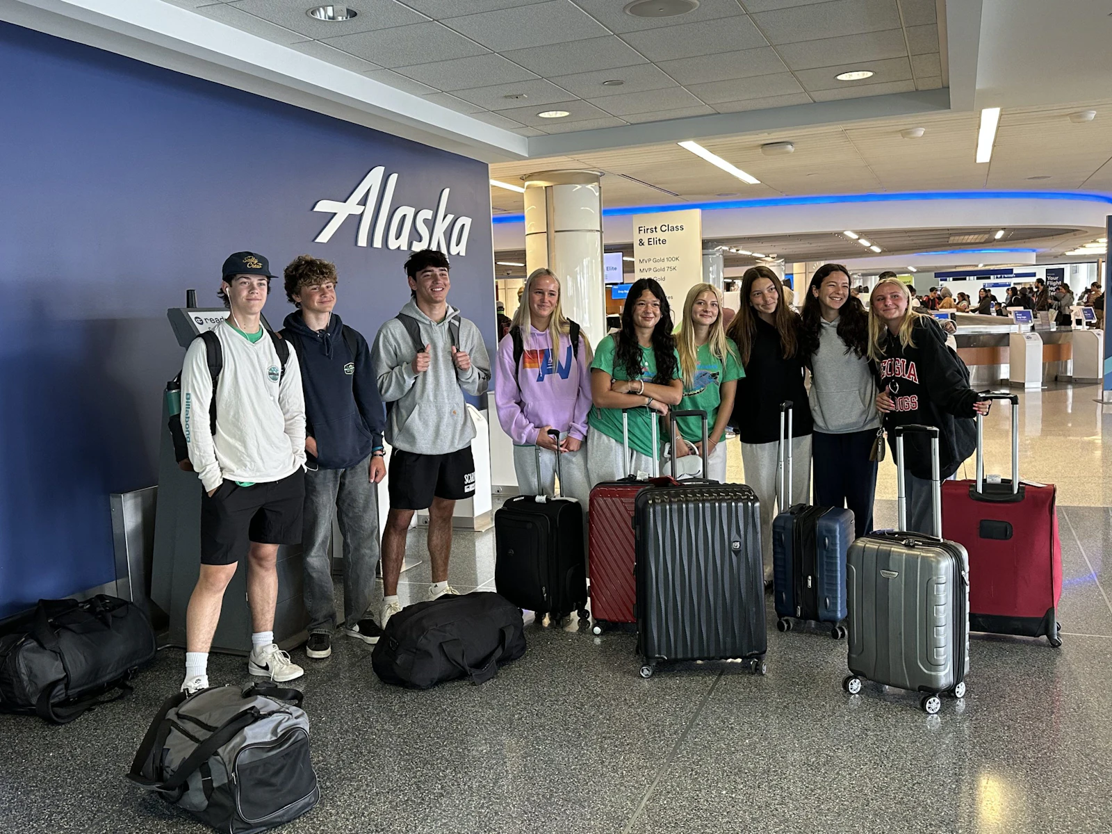 A Rustic Pathways student group stands with luggage in an airport terminal before a group flight