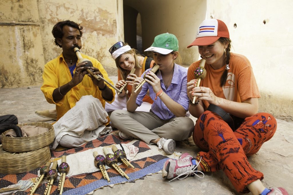 Rustic Pathways students playing a traditional instrument with a local during a student travel program in Asia.