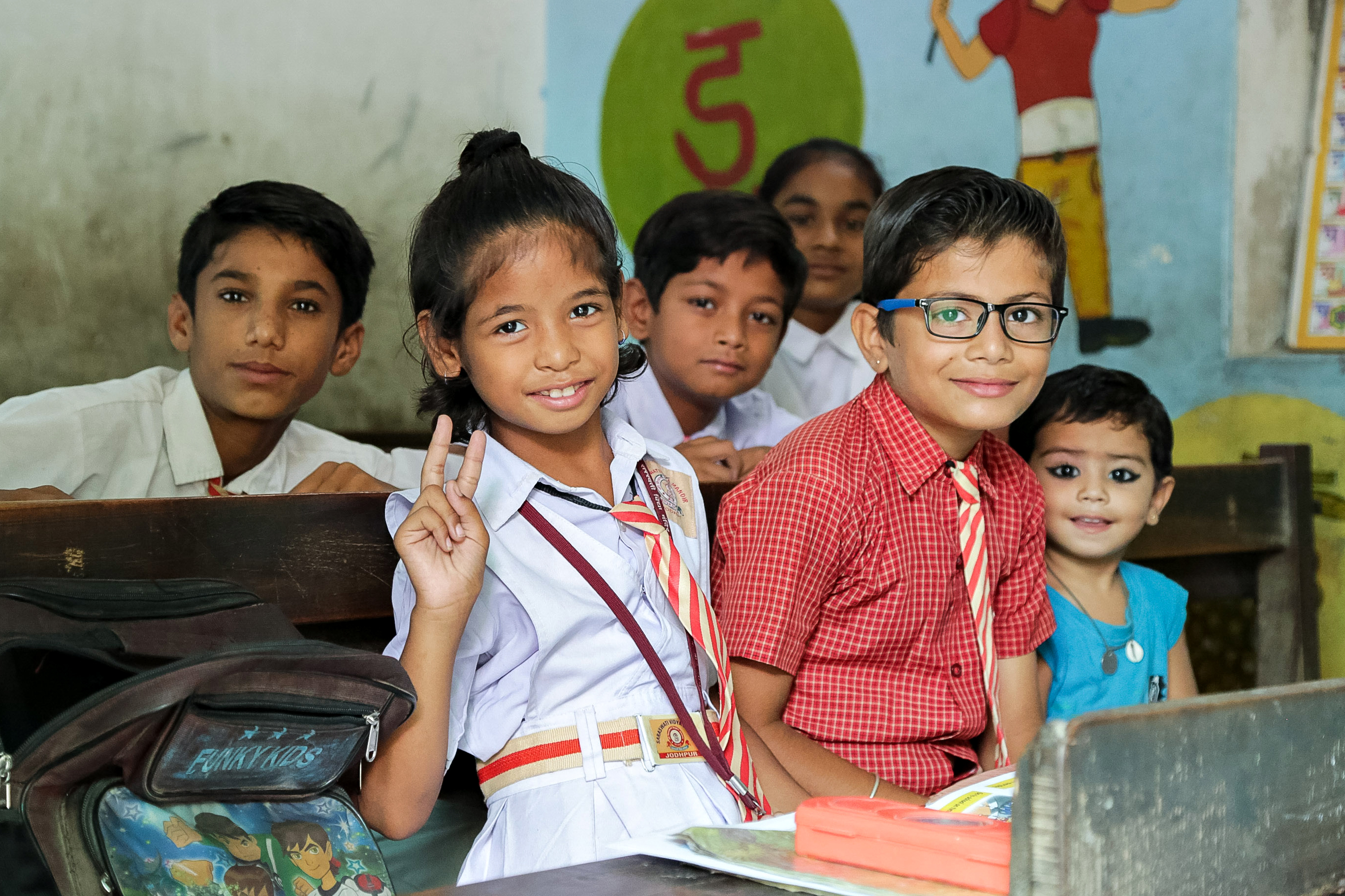 Schoolchildren in uniforms smile and pose in a classroom