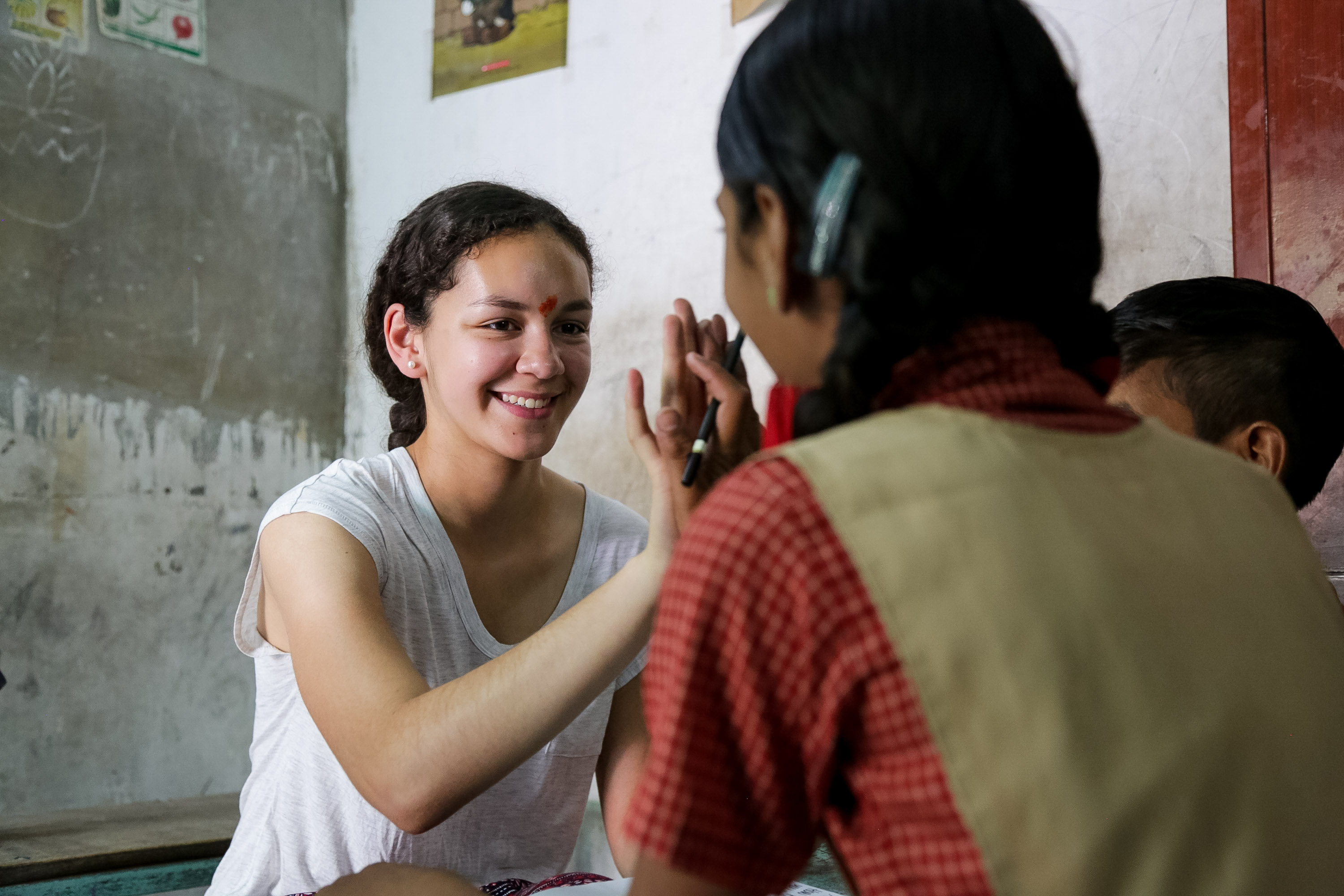 On a school trip, a student high-fives a local student in a classroom