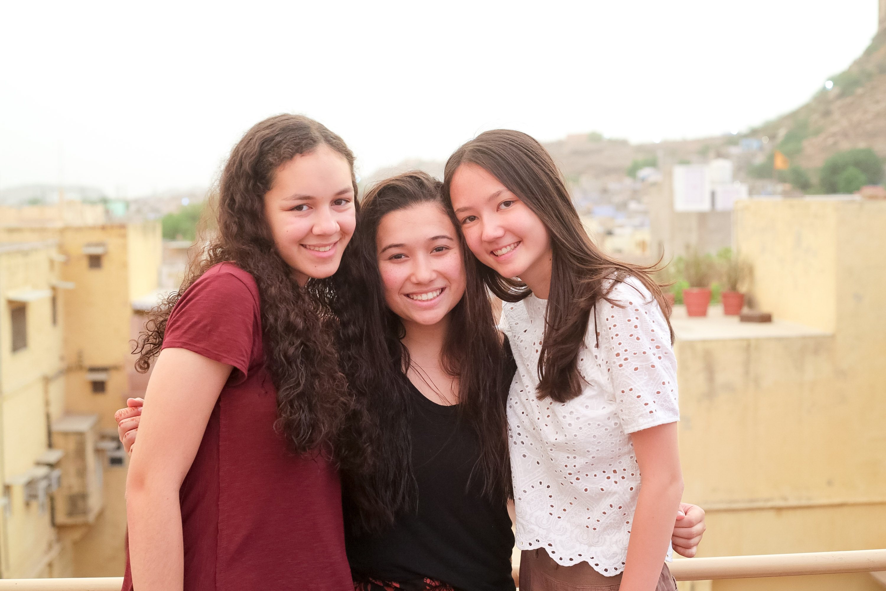 Students smile on a rooftop overlooking a hillside city in India