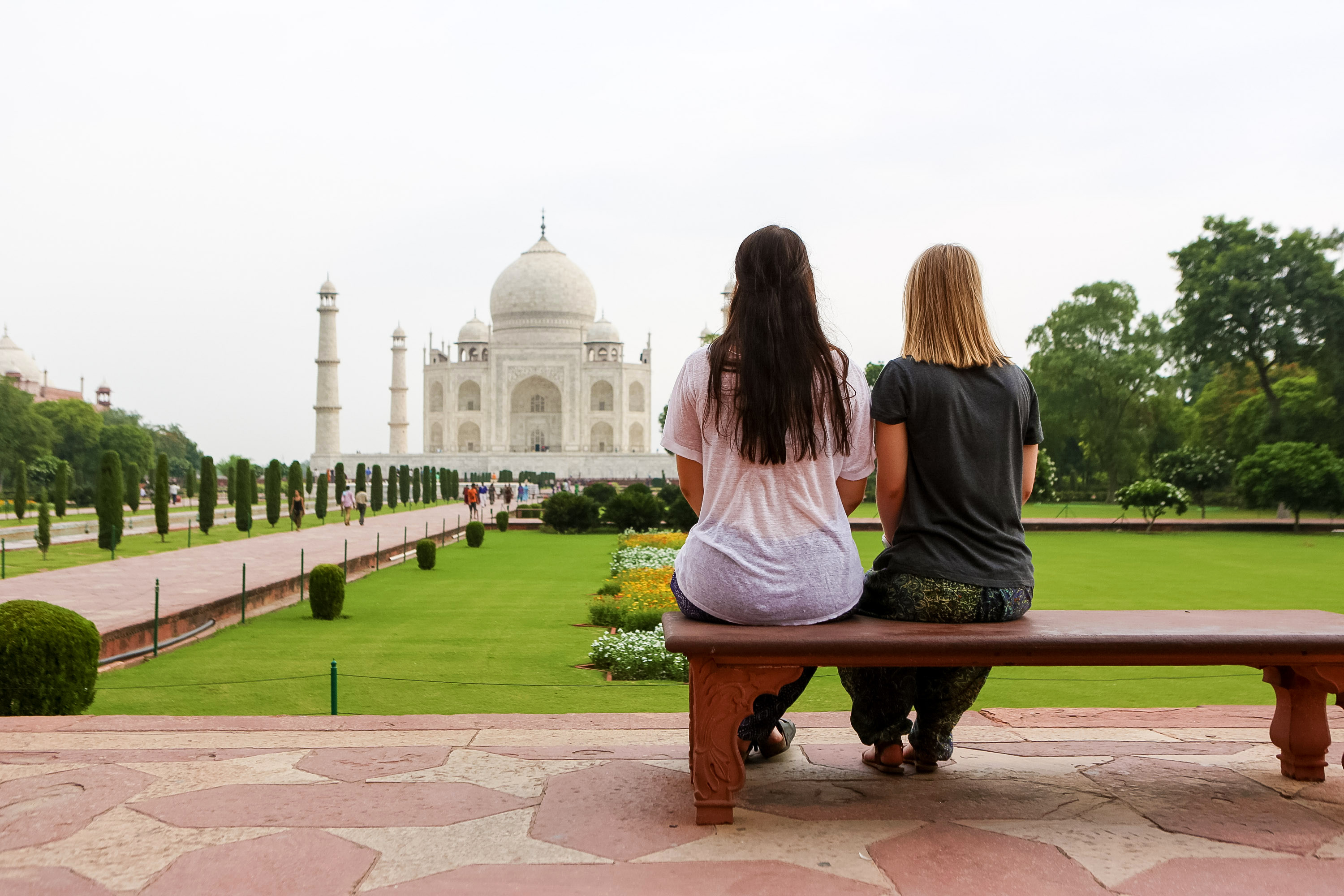 Students sit on a bench overlooking the Taj Mahal