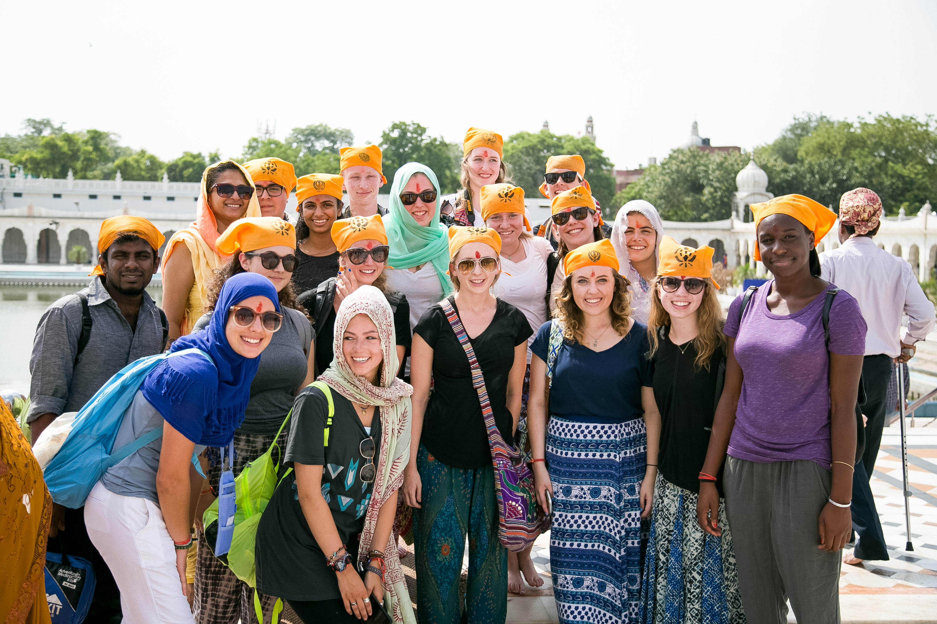 Students wearing orange head coverings pose together at a temple complex