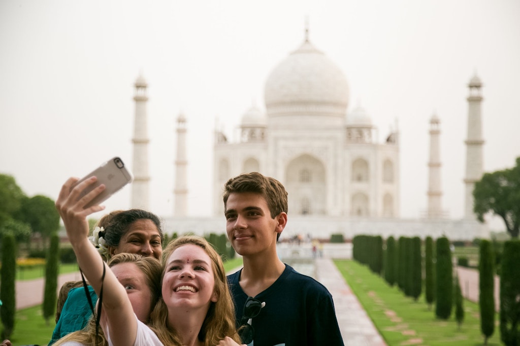 Group of students taking a selfie at the Taj Mahal while volunteering abroad in Asia, experiencing cultural exchange and community connection.