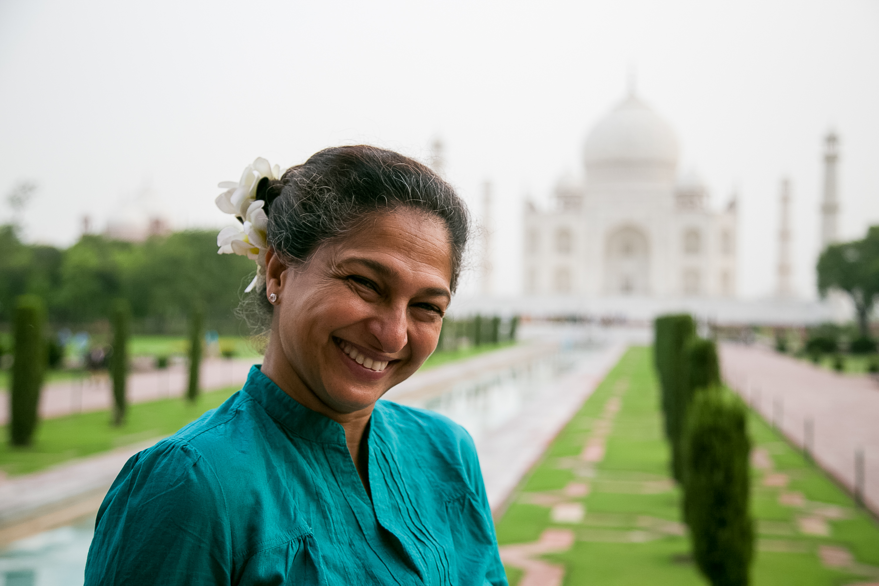 A woman smiles with the Taj Mahal rising behind her in India
